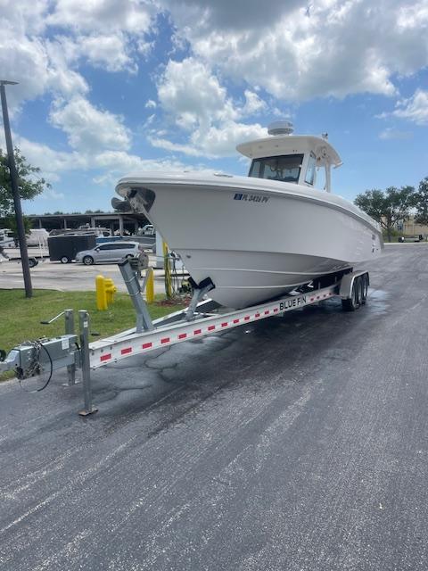 2014 Everglades 325 Center Console boat on trailer under cloudy sky.