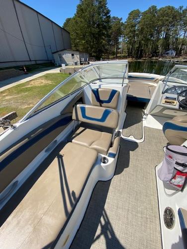 2005 Bayliner 249 SD boat interior with beige seating and clear windshield, docked near trees.