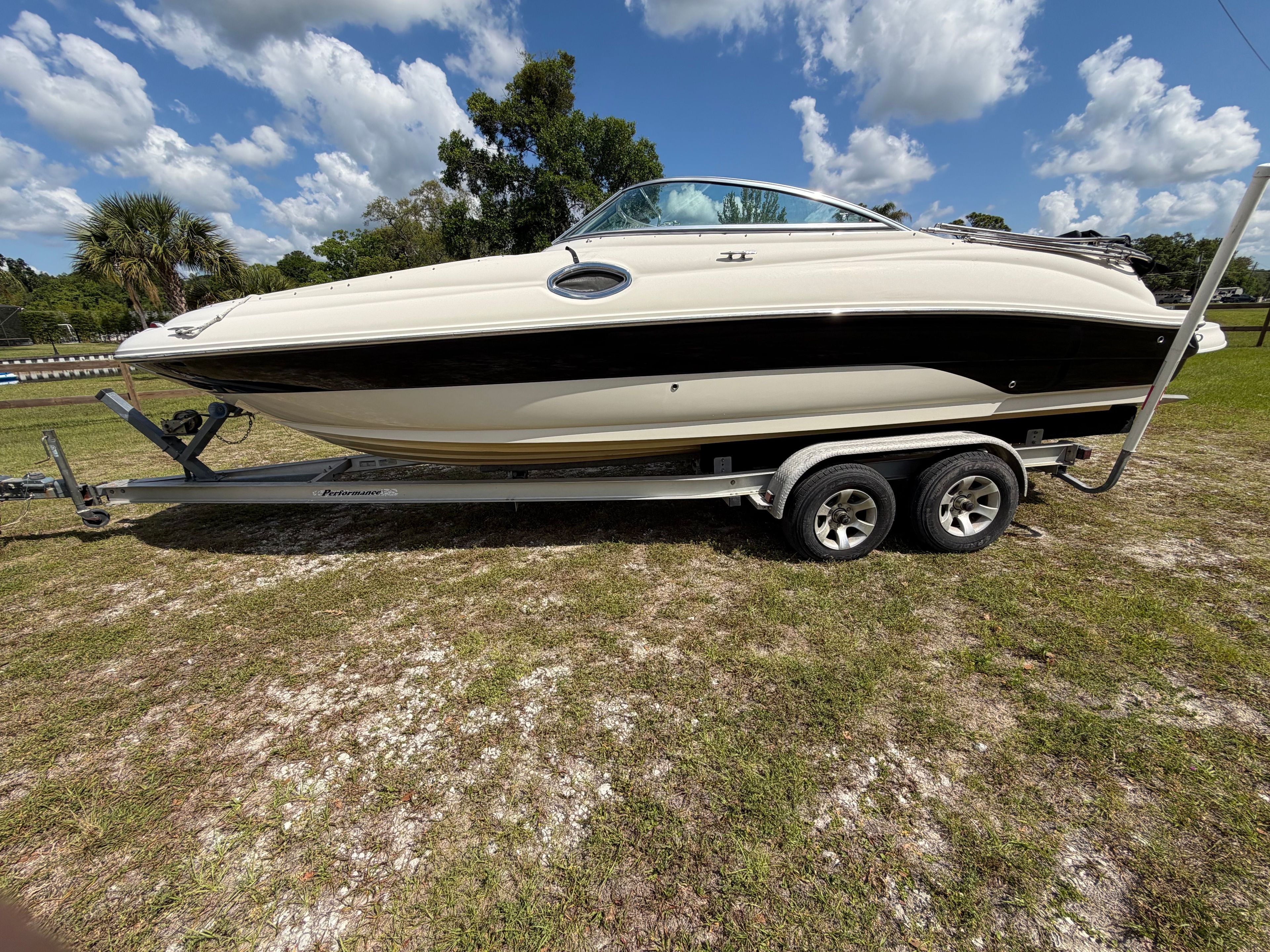 A 2004 Custom Sea Ray Bow Rider on a trailer, parked on grass.