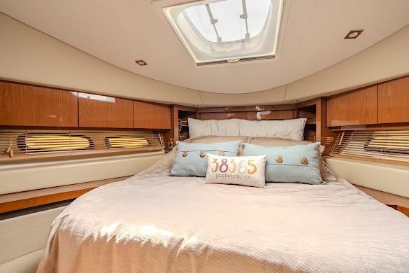 Luxurious bedroom interior of 2016 Sea Ray Sundancer 510 yacht with skylight and elegant bedding.