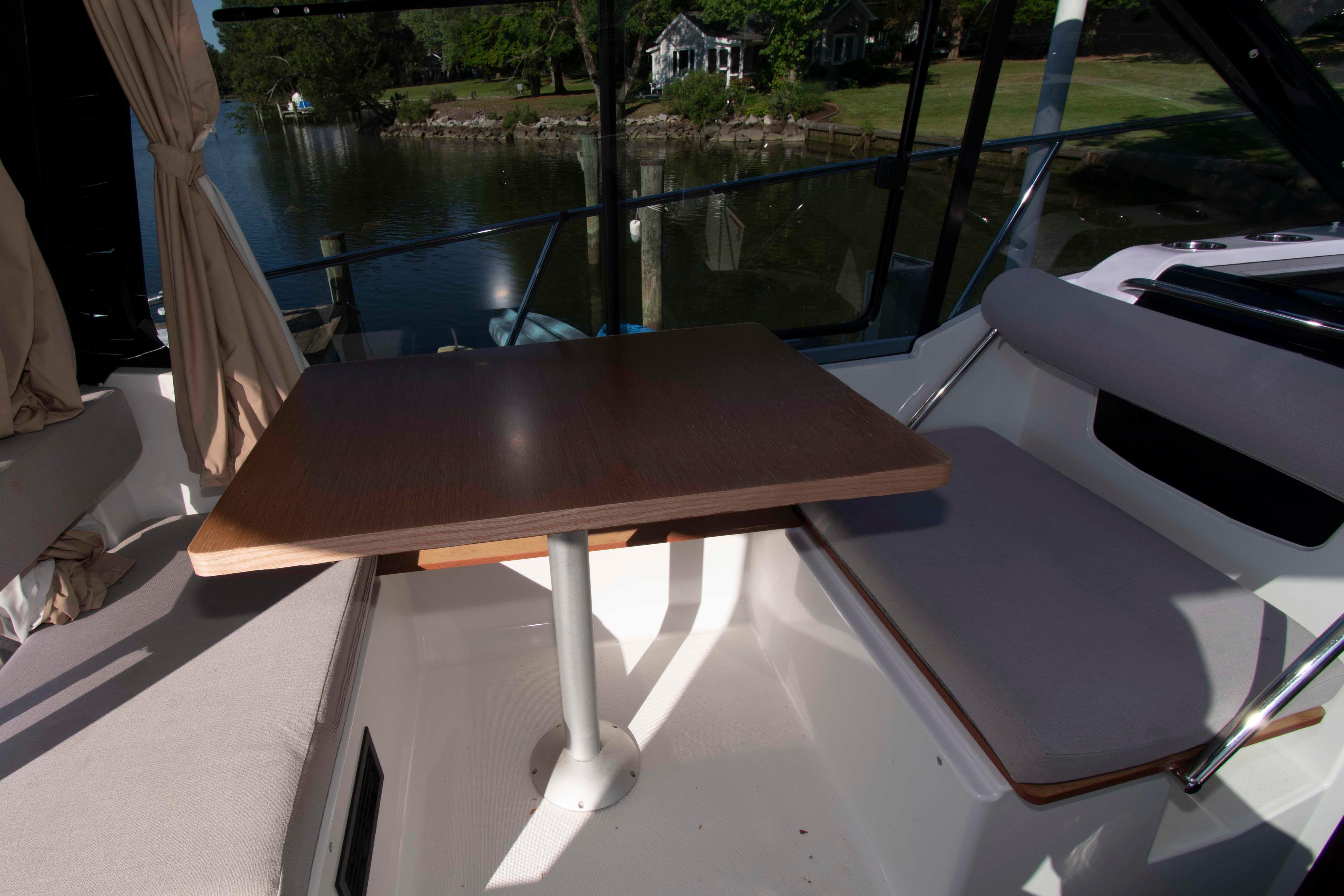 Interior of 2017 Jeanneau NC 895 boat with table and seating by the water.