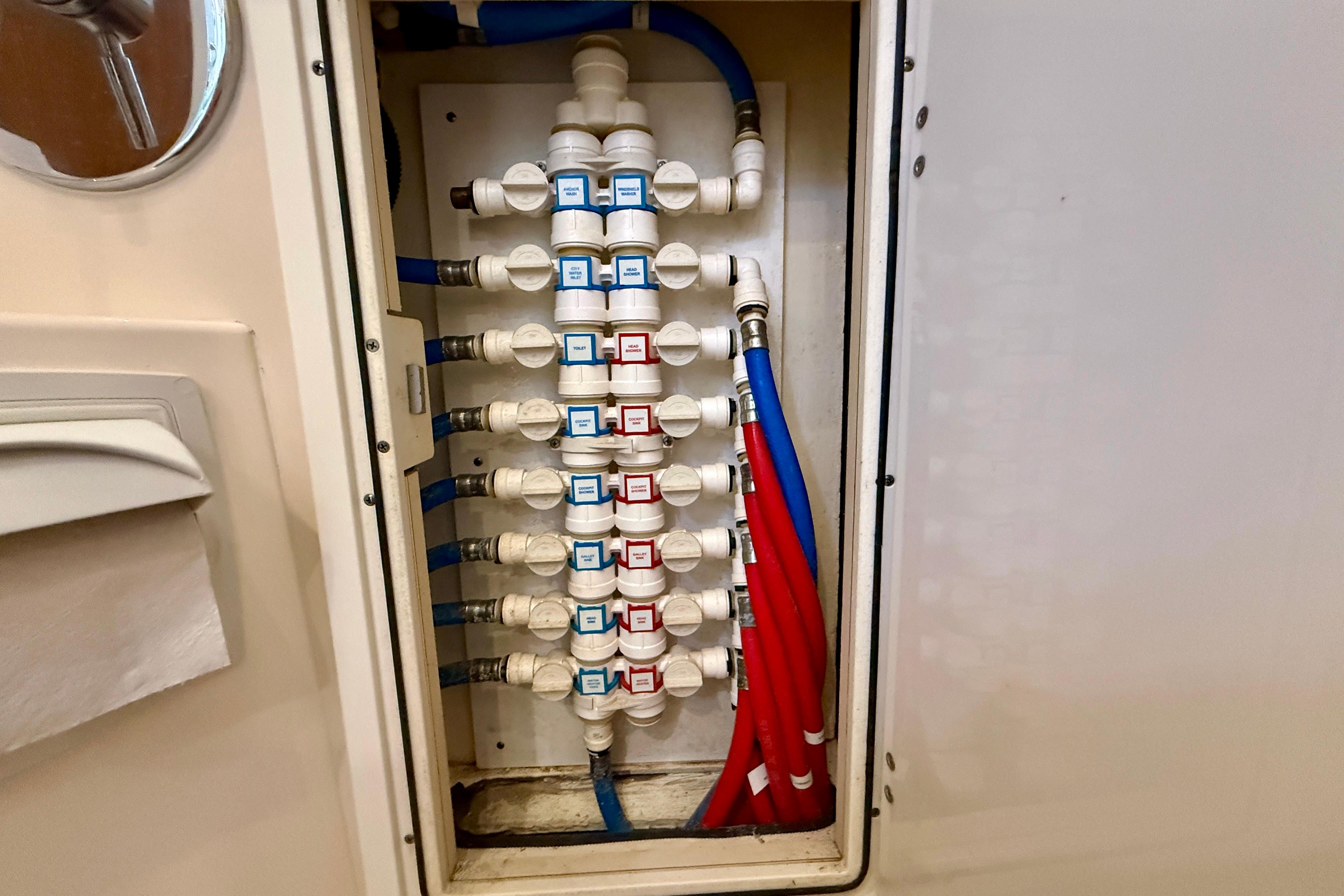 Plumbing system inside a 2012 Pursuit OS 345 Offshore boat, featuring labeled valves and colored pipes.