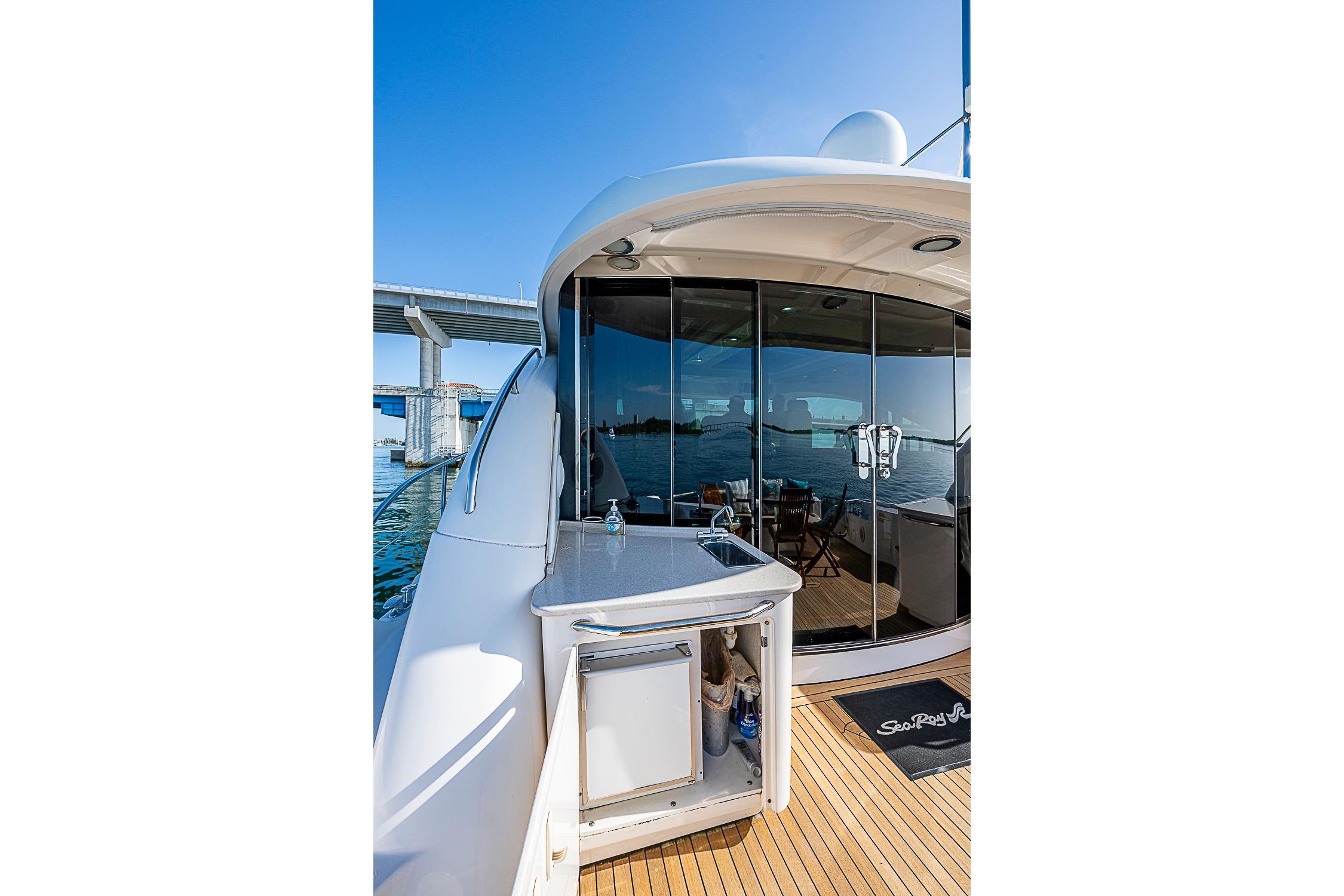 2008 Sea Ray 60 Sundancer yacht with outdoor kitchenette and glass doors, docked near a bridge.