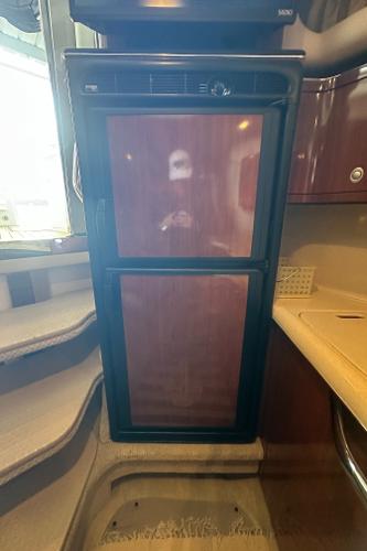 2004 Sea Ray 380 Sundancer interior with compact refrigerator and wooden cabinetry.