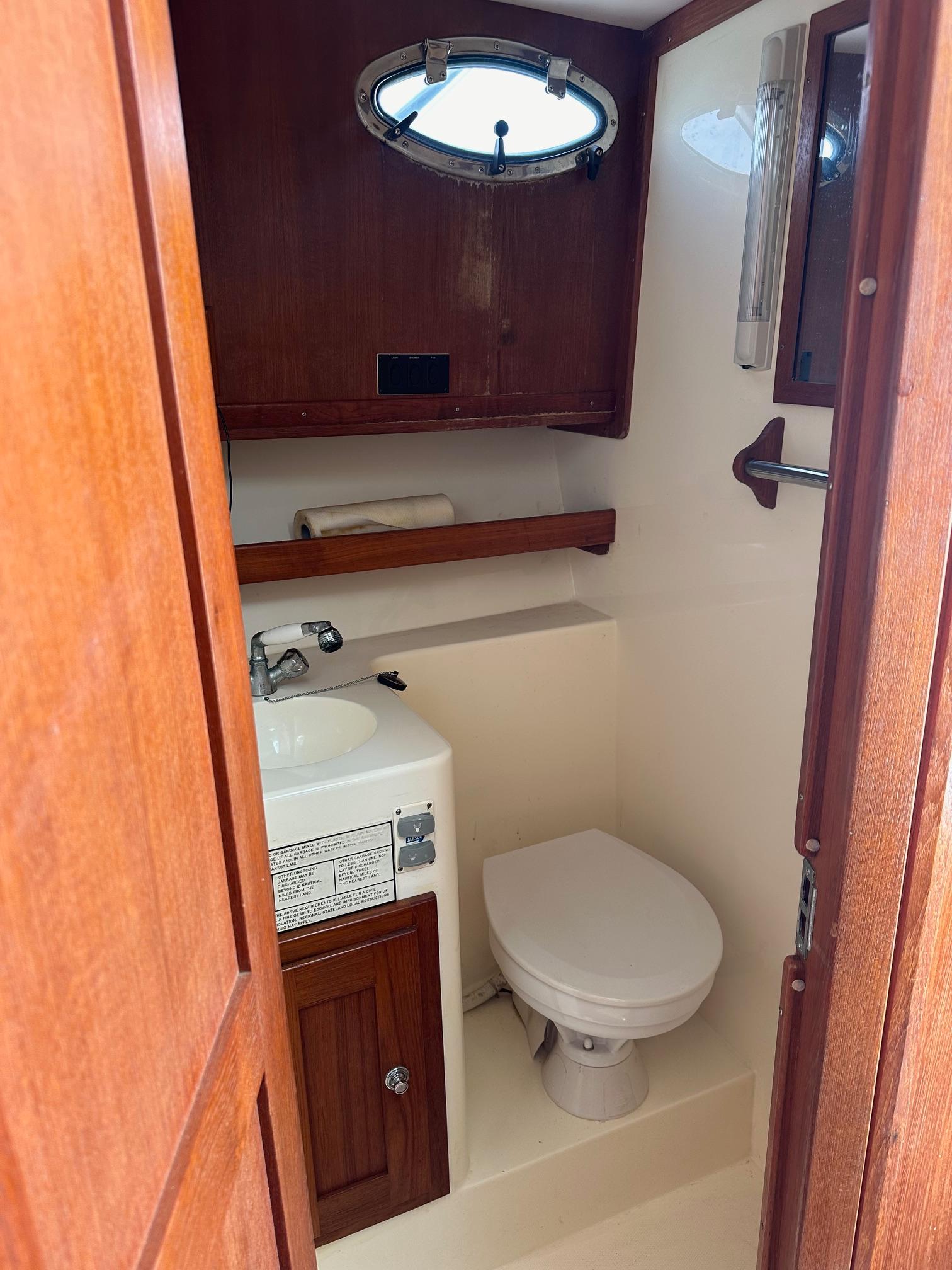 2006 Albemarle 320 Express Fisherman boat bathroom with sink, toilet, and wooden cabinetry.