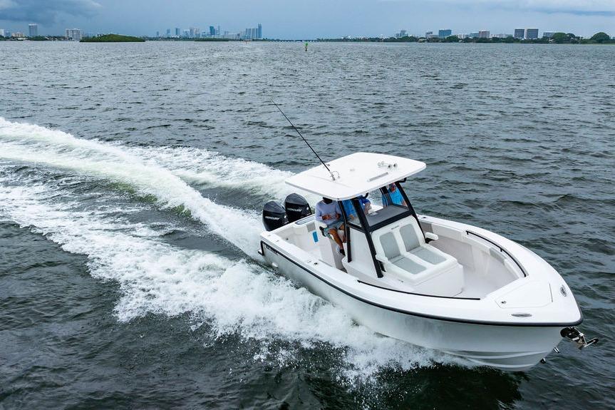 2027 Reef Runner 280 boat cruising on open water with city skyline in background.