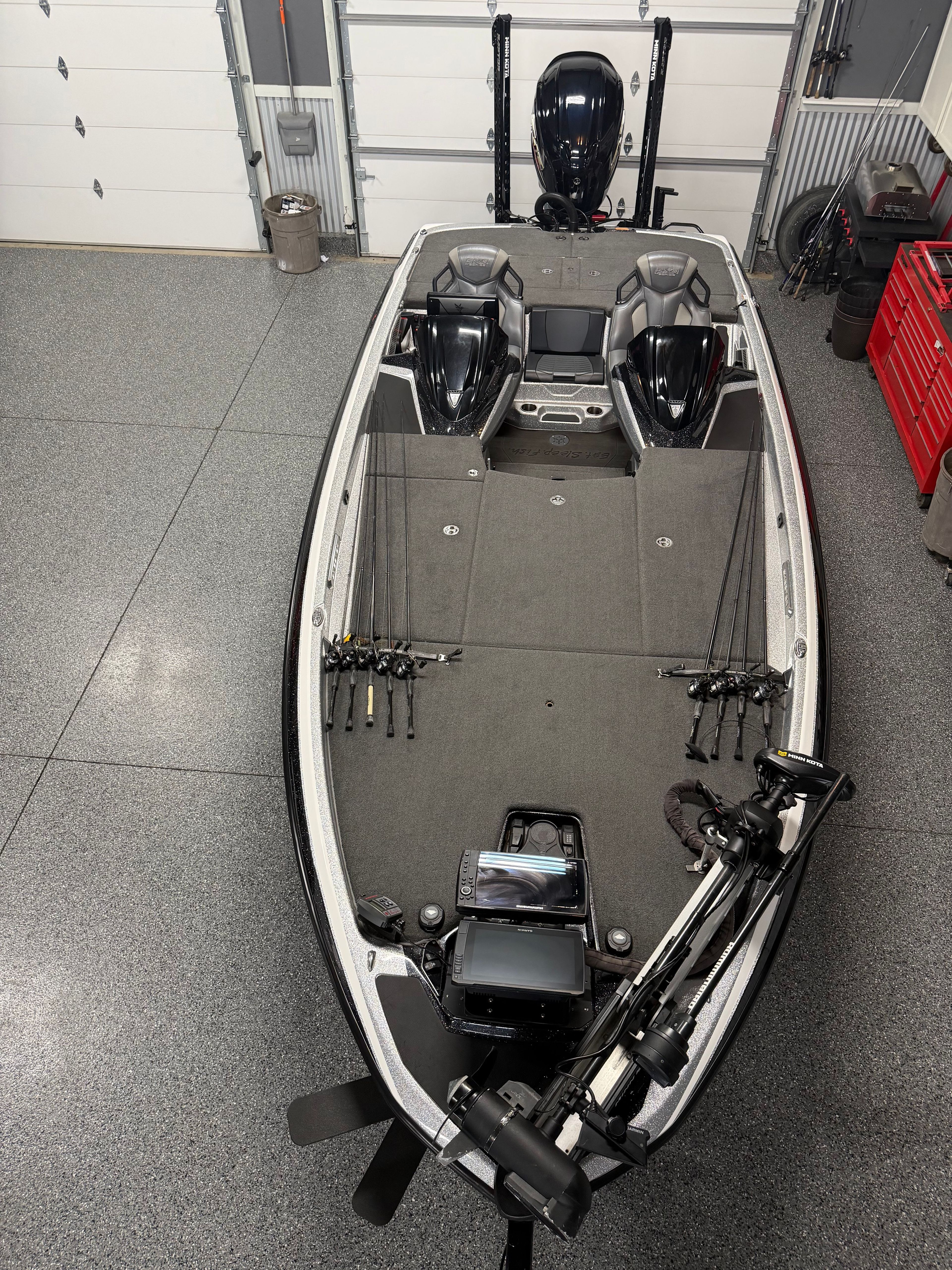 A modern fishing boat in a garage with fishing gear and engines.