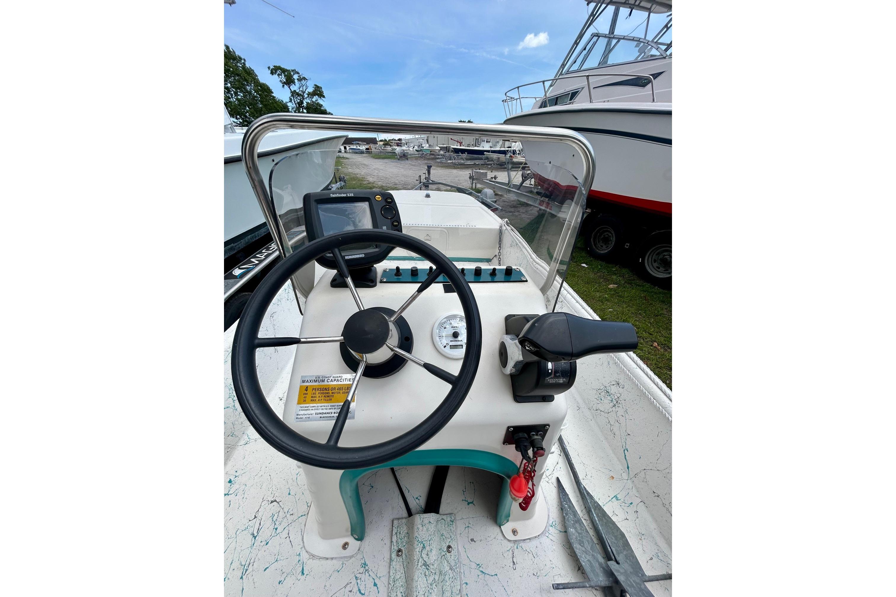 2002 Sundance K16CC boat console with steering wheel and controls, docked outdoors.