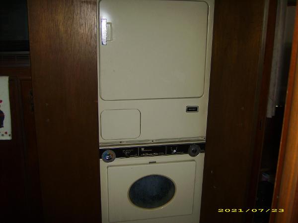 Vintage stacked washer and dryer unit in a wooden interior, dated 2021.