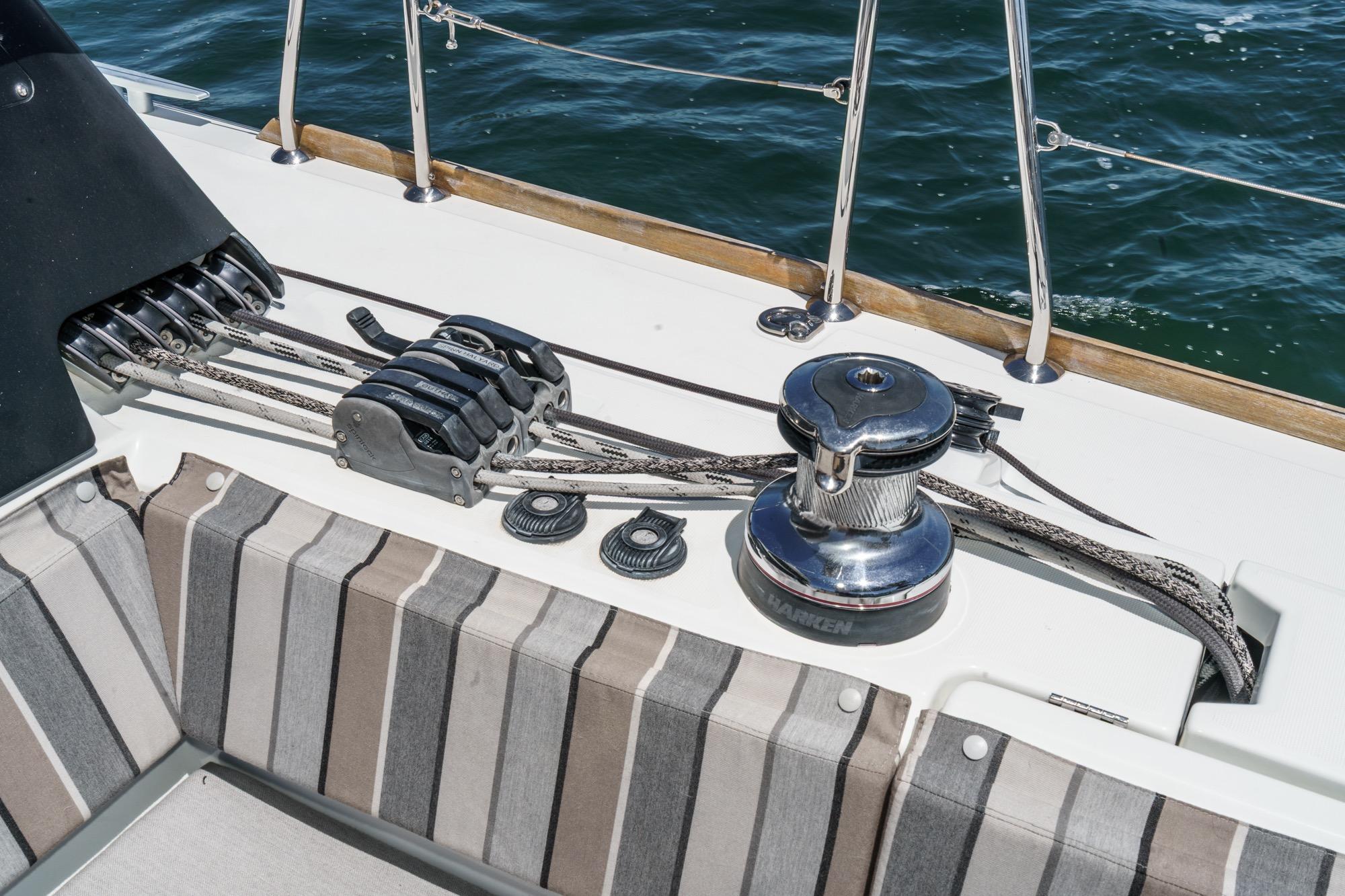 Deck of 2017 Beneteau Sense 50 yacht with winch and striped seating.