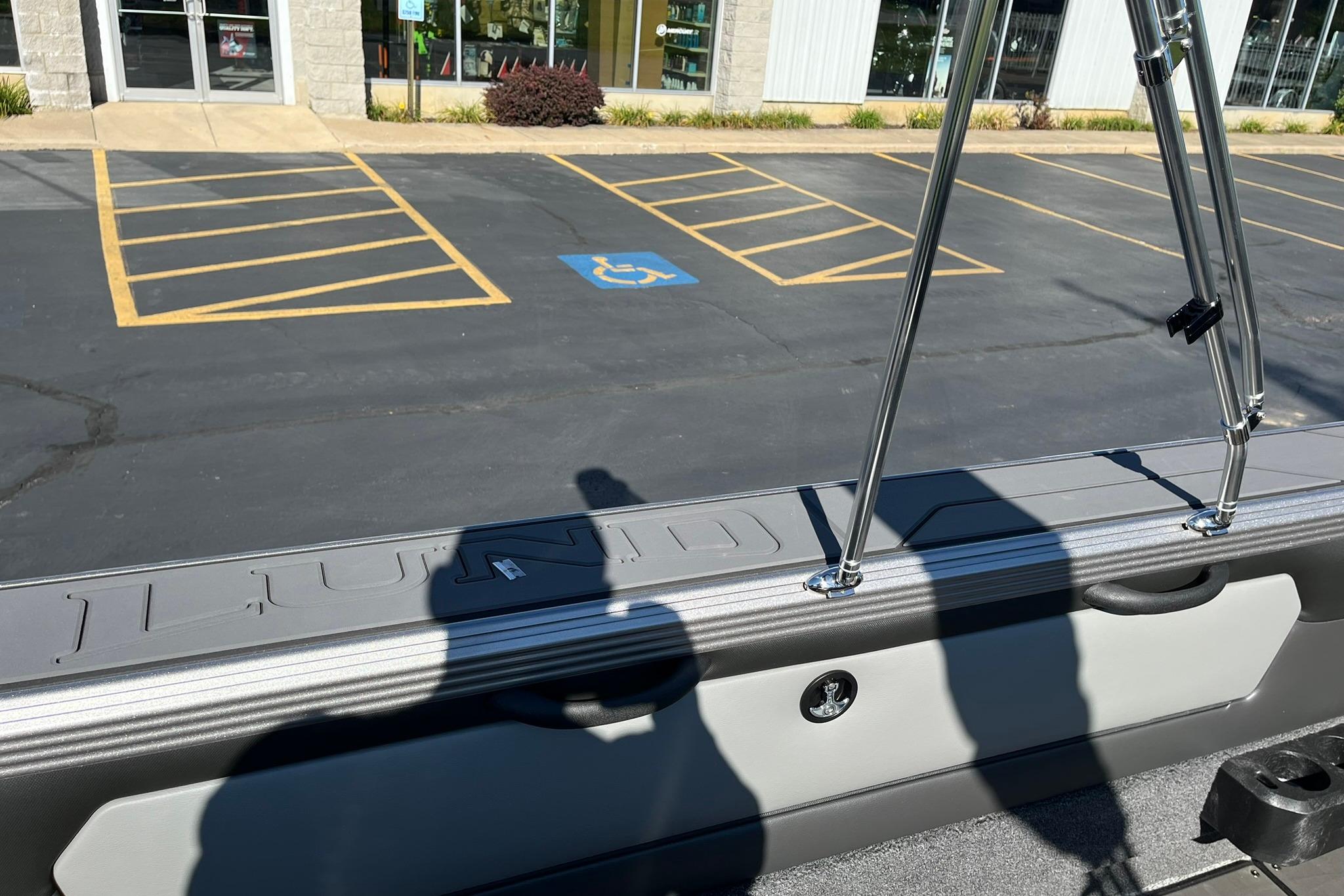 2026 Lund 2275 Baron boat detail with chrome railings and parking lot background.
