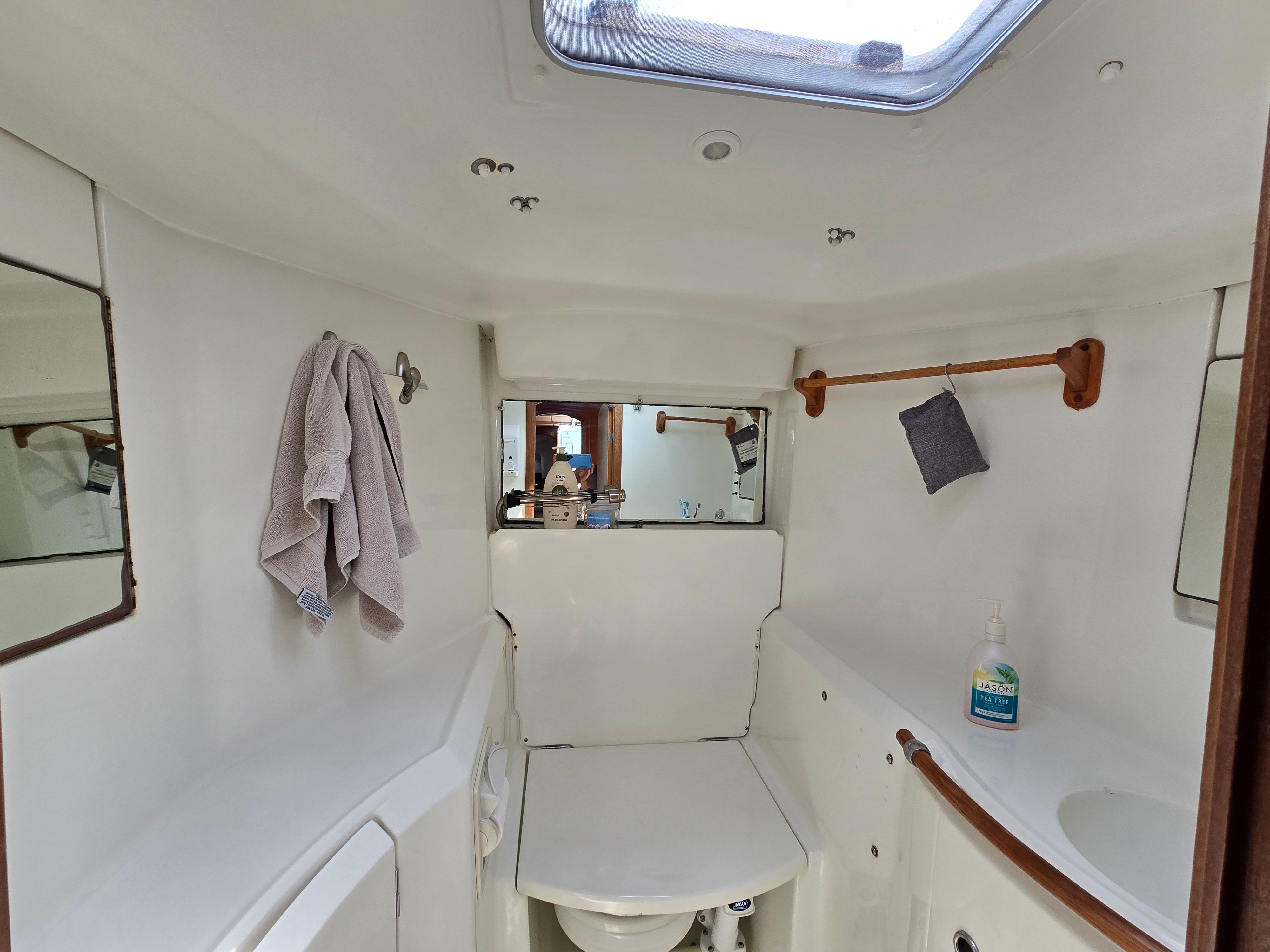 Interior view of a boat bathroom with toilet, sink, and towel rack.