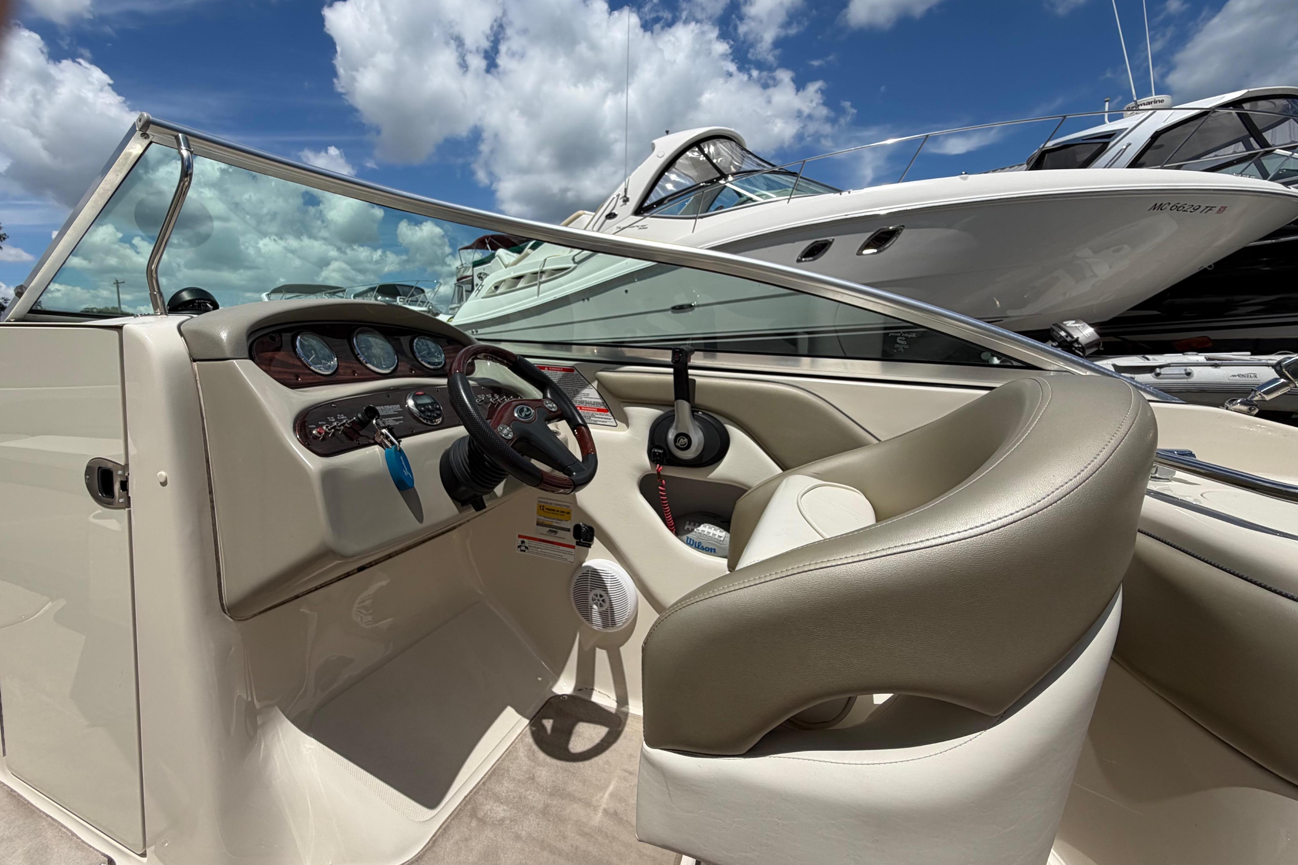 2004 Sea Ray 240 Sundeck boat interior with steering wheel and dashboard under blue sky.