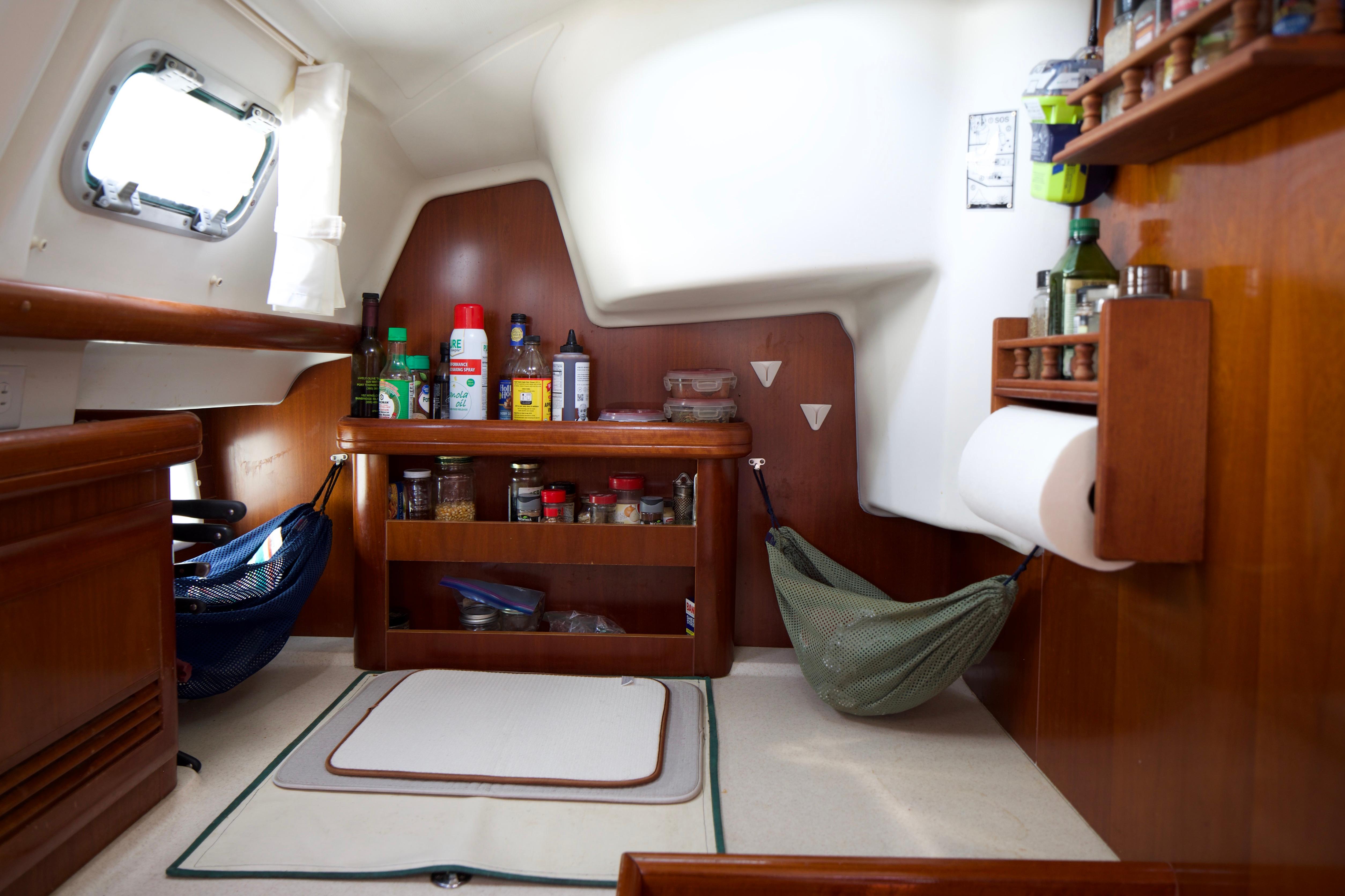 Interior of 2005 Beneteau 423 sailboat kitchen with wooden cabinetry and storage shelves.