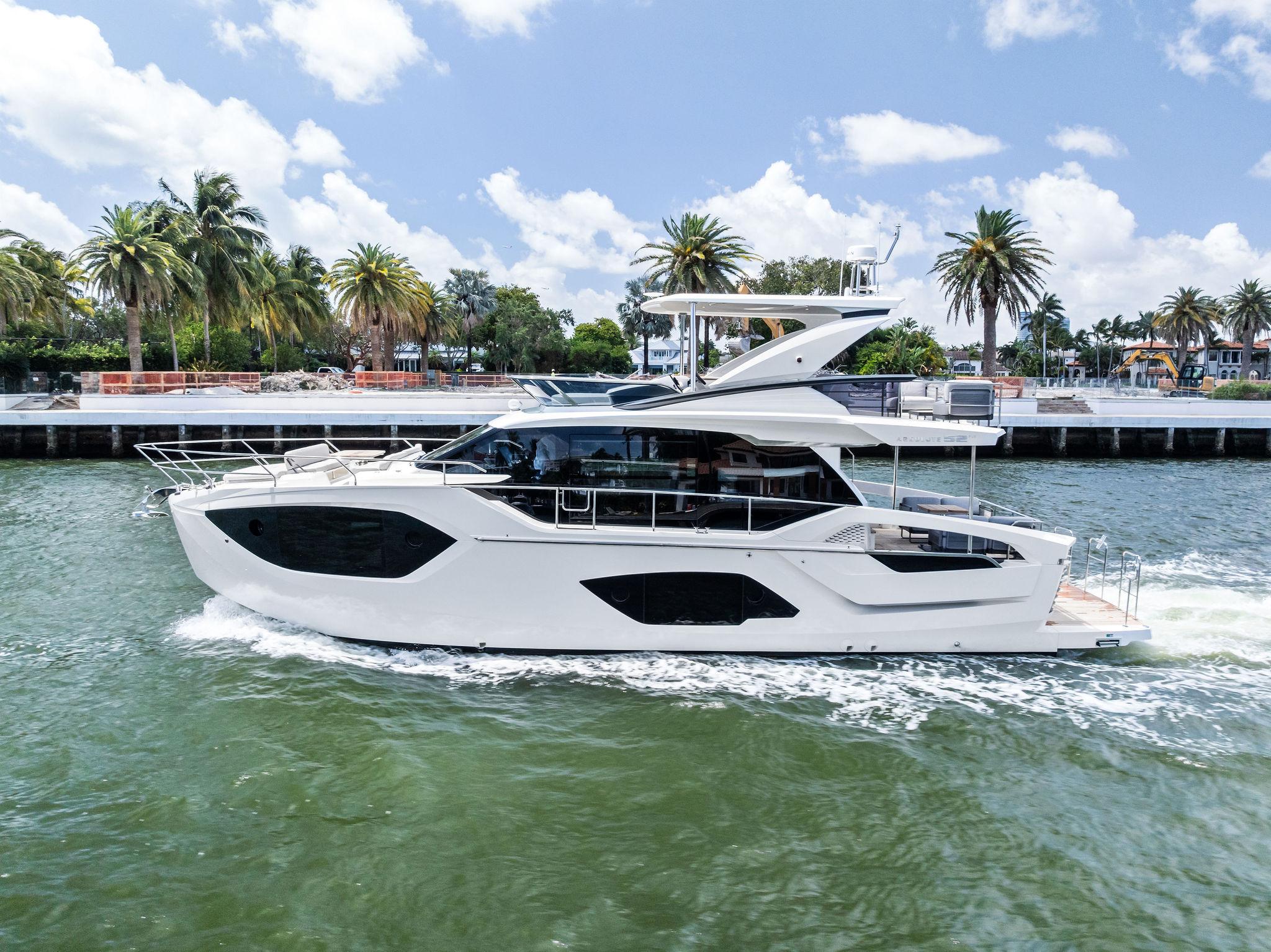 2023 Absolute 52 FLY yacht cruising on a sunny day, surrounded by palm trees and blue skies.