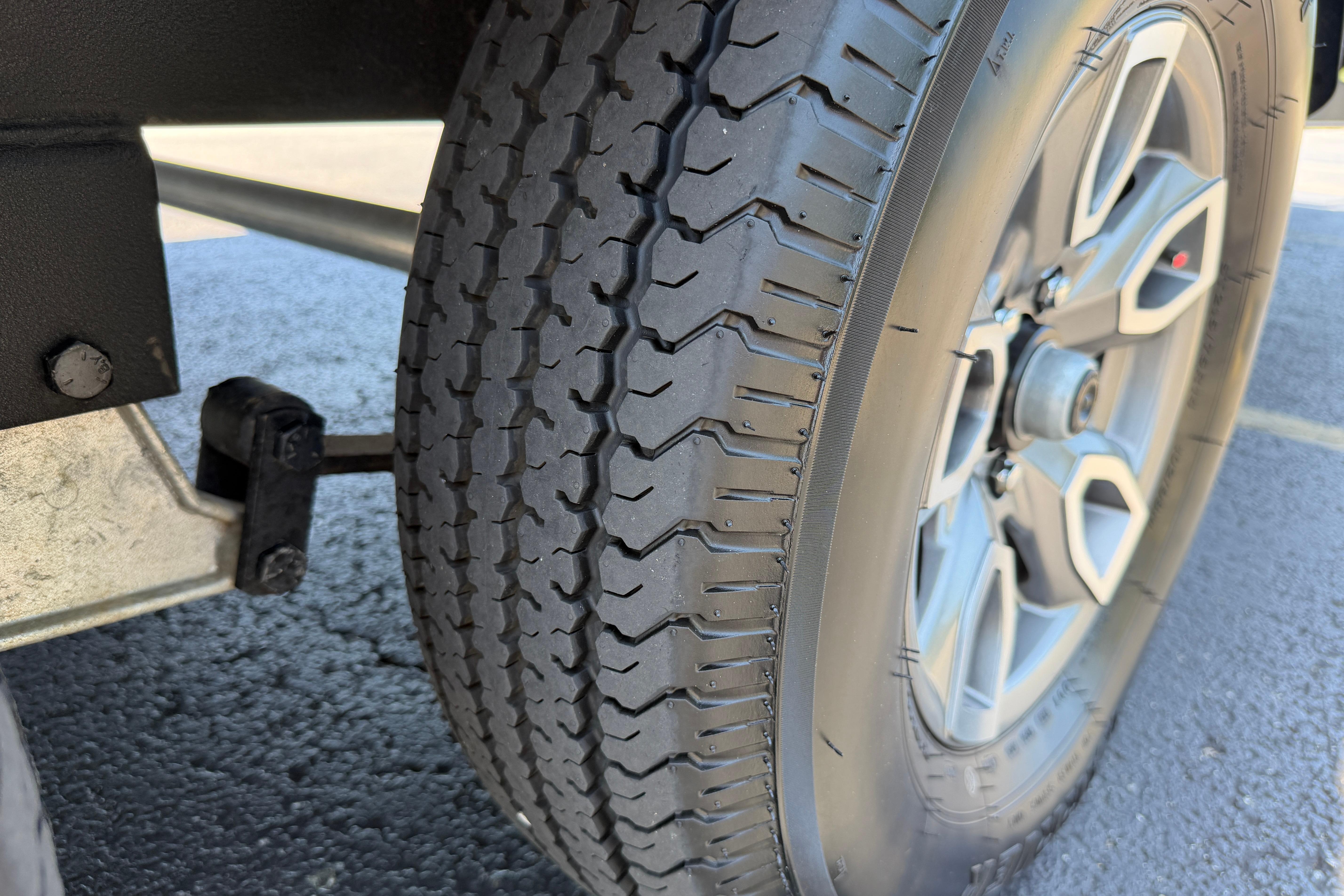 Close-up of a 2024 Regency R250DL3 tire and wheel on asphalt.