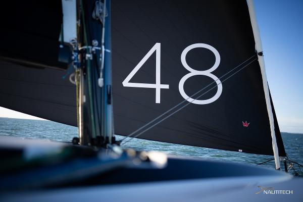 Sailing yacht Nautitech 48 Open, 2025 model, with black sail on open water.