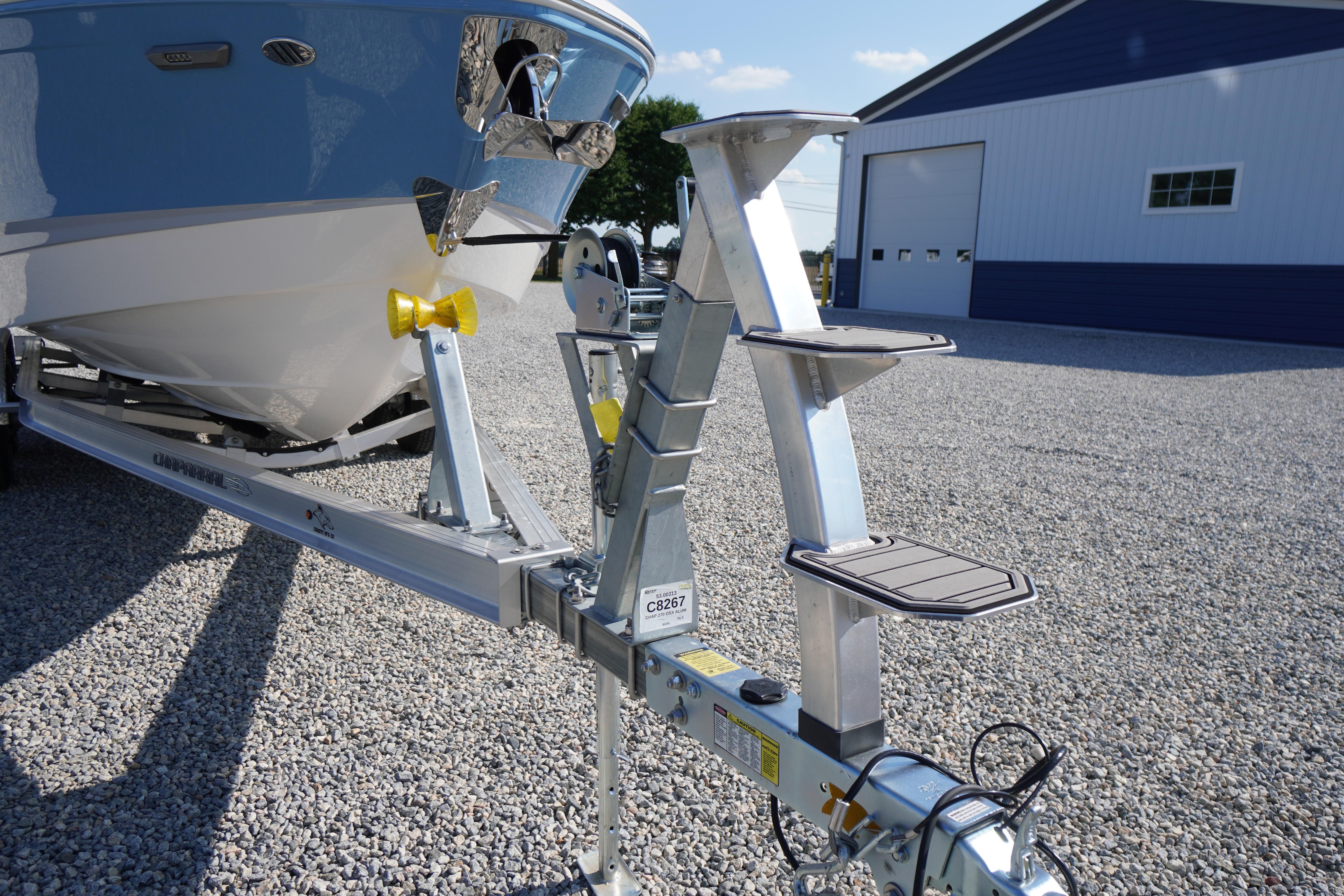 2026 Chaparral 270 OSX boat on trailer, parked on gravel near a blue building.