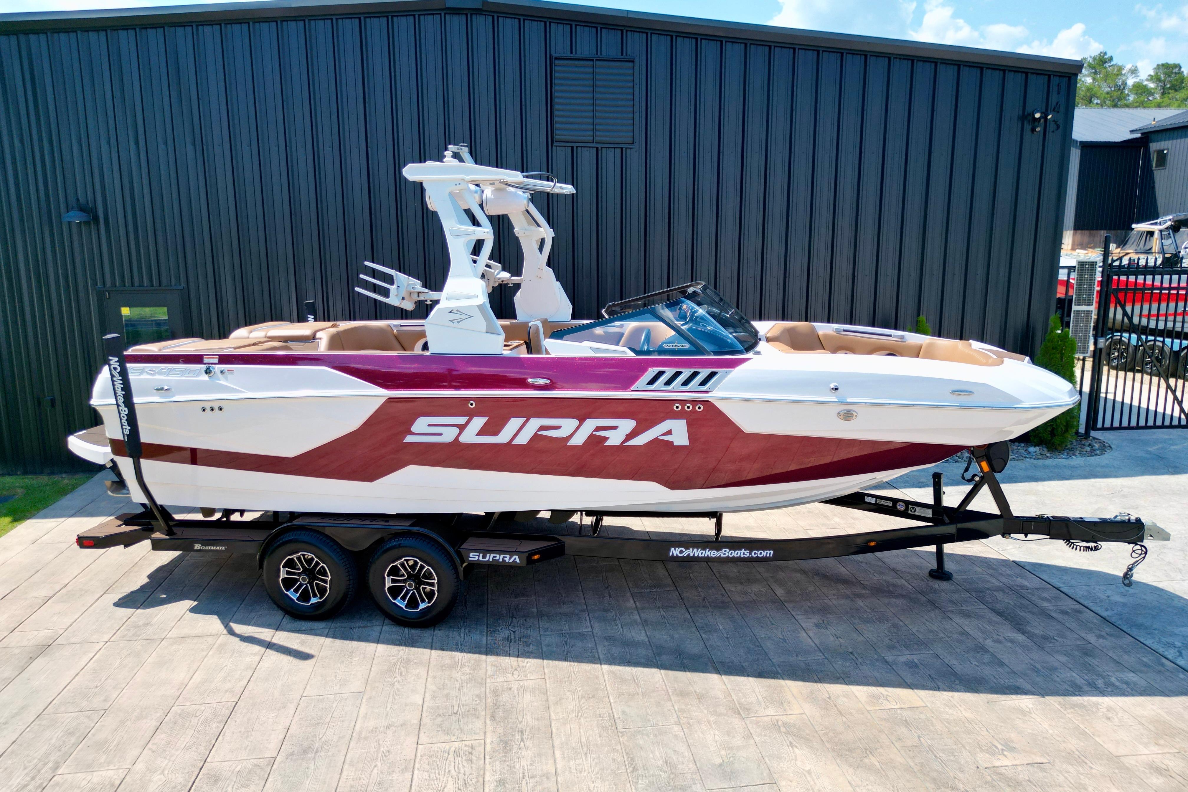 2021 Supra SE boat on trailer, parked outdoors near a black building.