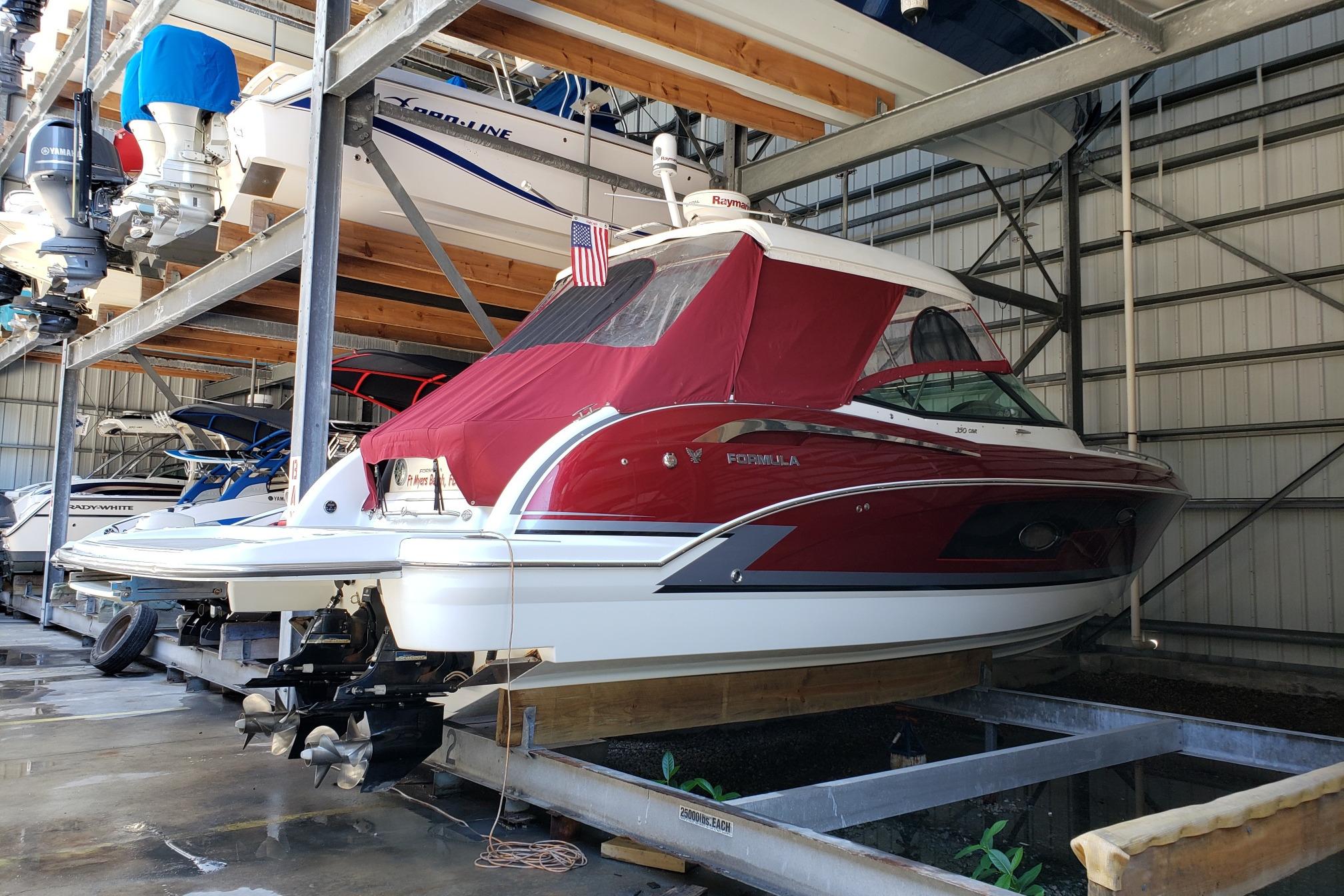 2015 Formula 350 Crossover Bowrider in storage, red cover, American flag displayed.