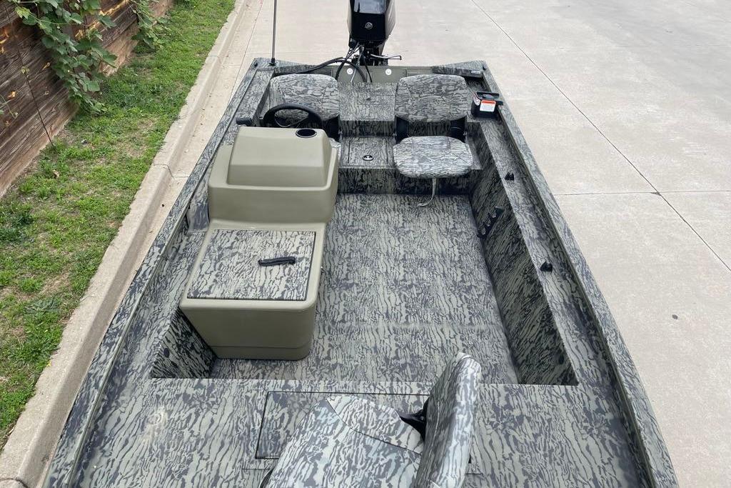 2026 Tracker Grizzly 1754 SC boat with camouflage interior, parked on concrete.