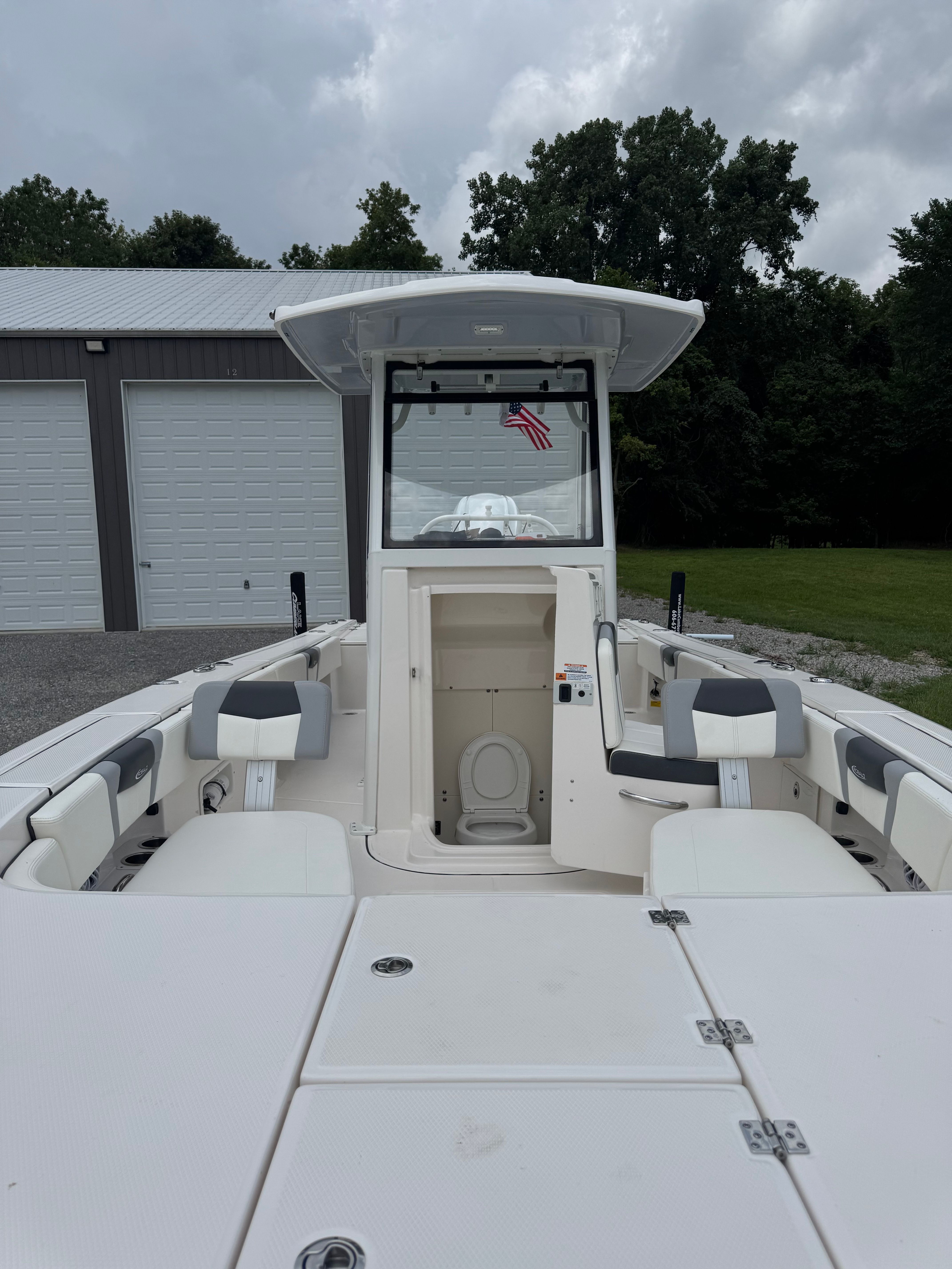 Robalo 266 Cayman 2023: A modern boat with spacious deck and seating, positioned in front of a garage.