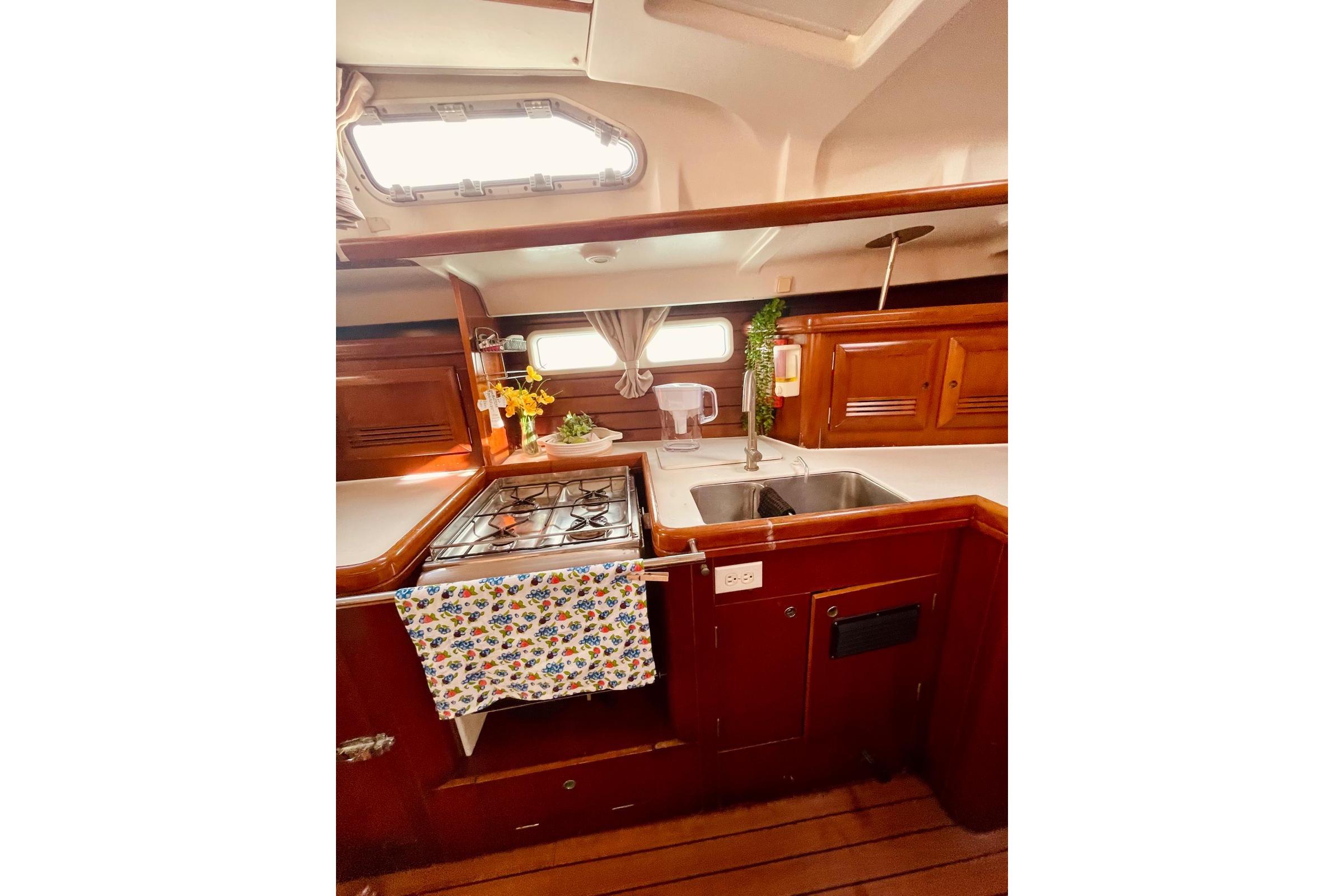 2005 Beneteau Oceanis 473 yacht kitchen with stove, sink, and wooden cabinetry.