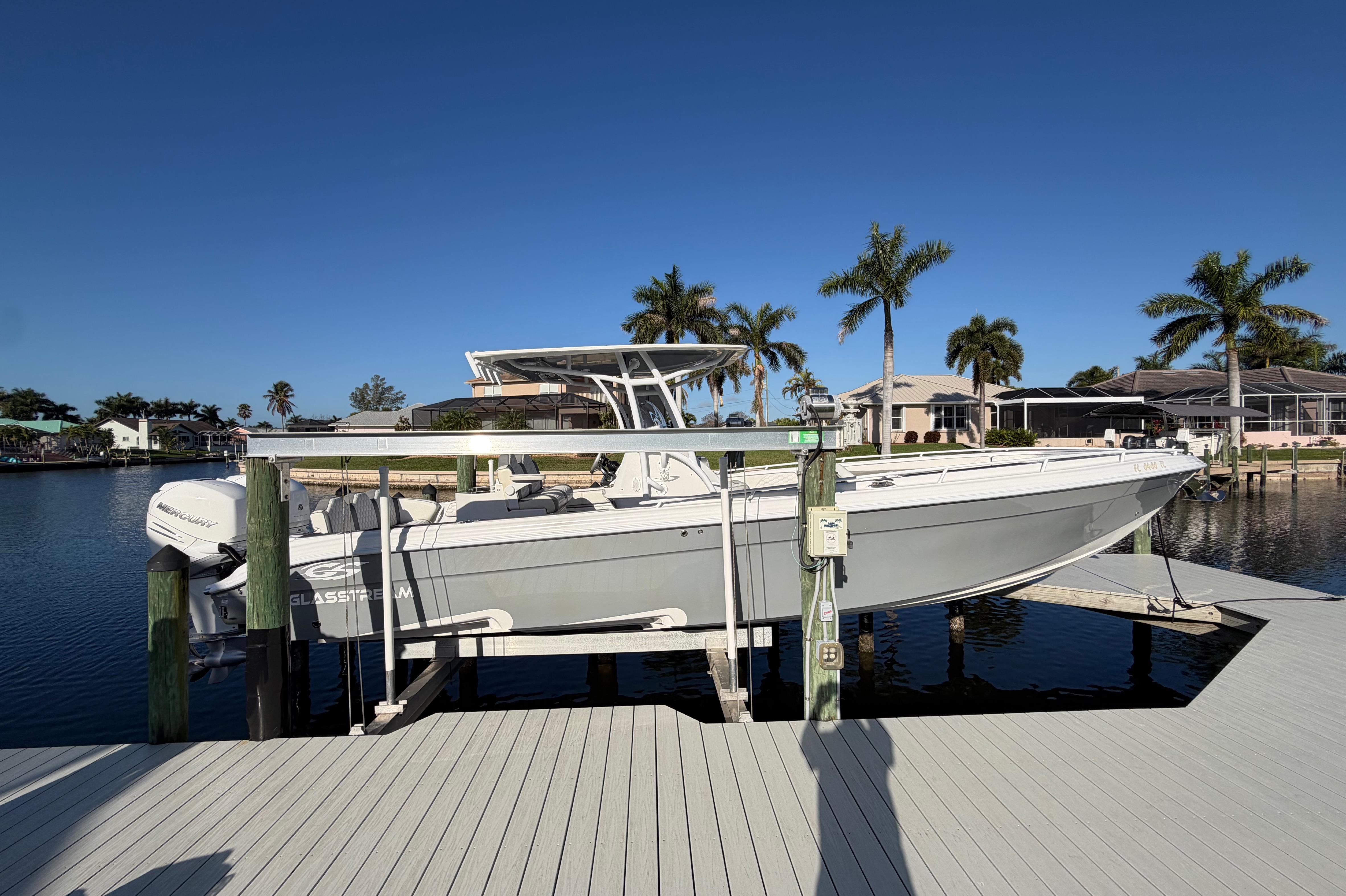 2022 Glasstream 328 Pro-XS boat docked by waterfront homes and palm trees.