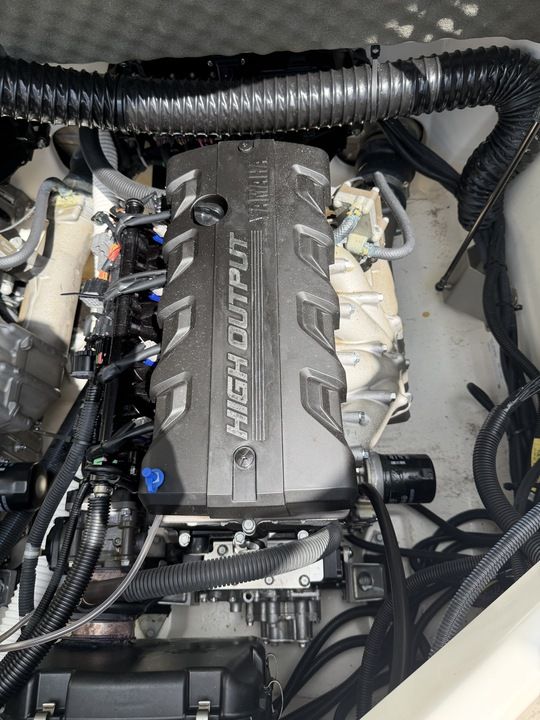 The engine compartment of a 2022 Yamaha 212SD boat shows a high-output engine with cables and hoses.