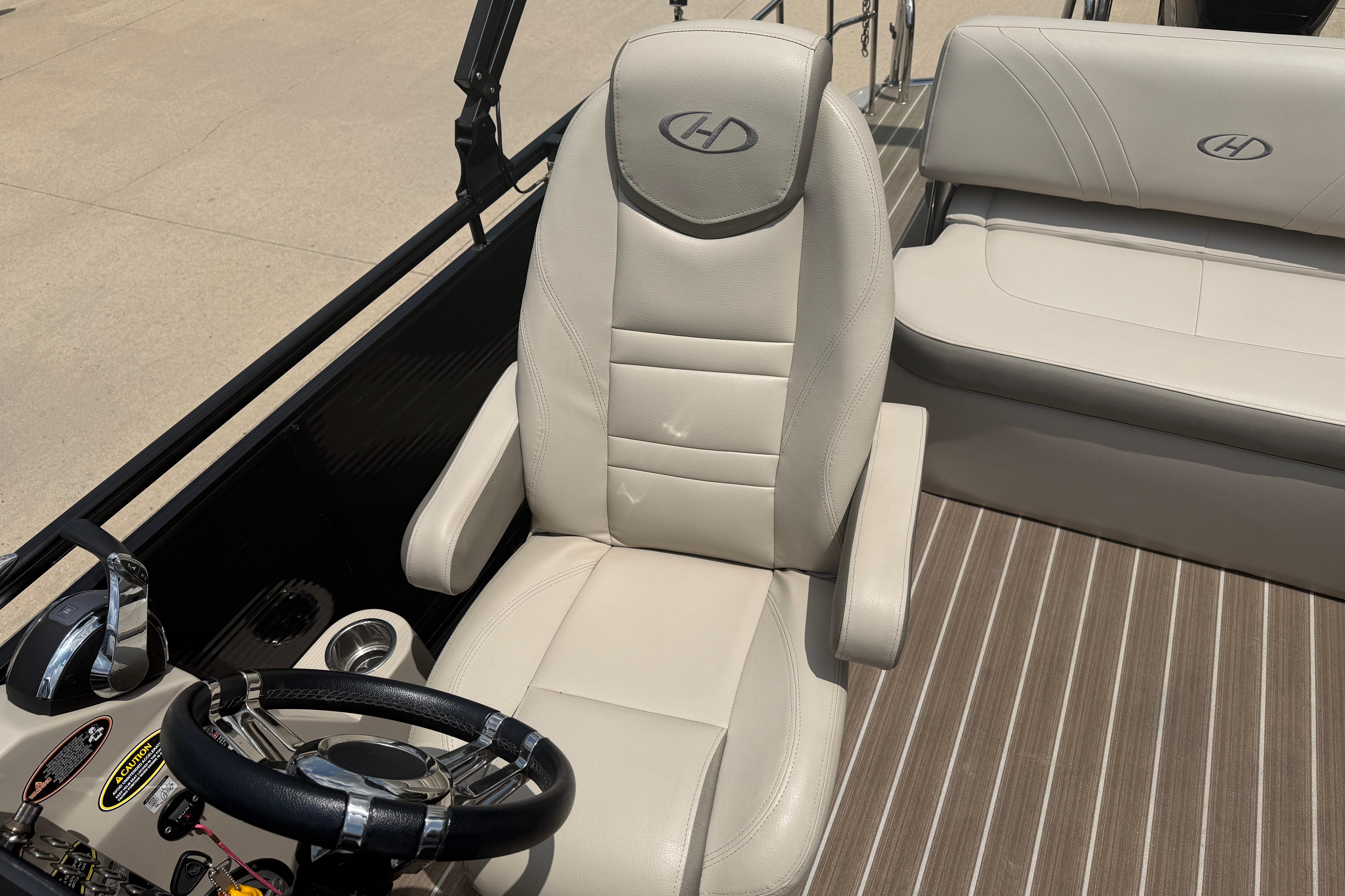 Captain's chair and helm of 2019 Harris Solstice 240 pontoon boat, featuring sleek design.