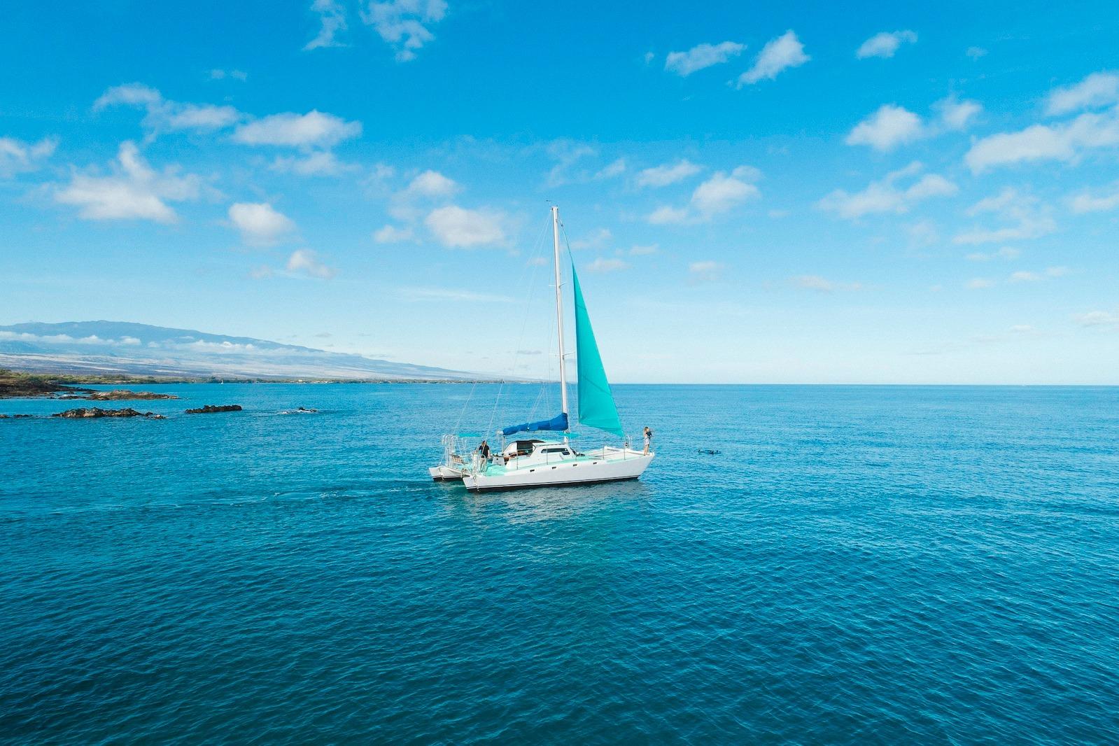 Vintage 1978 CSK Beach Cat sailboat cruising on a clear blue ocean under a bright sky.