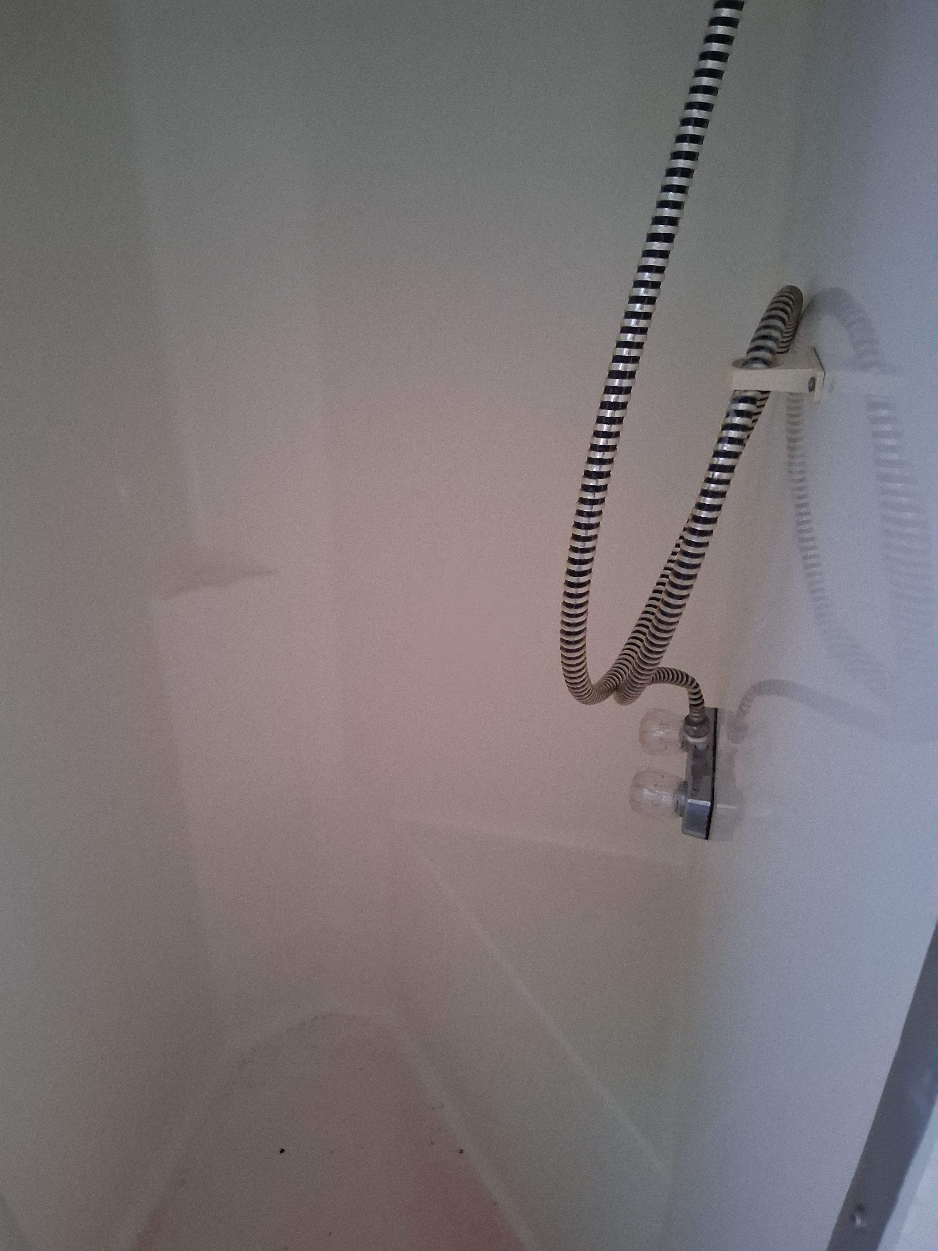 A shower stall with a flexible shower hose and faucet inside a boat.