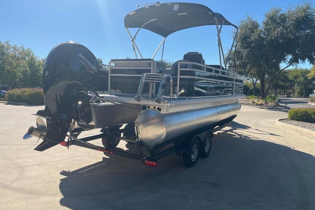 2026 Sun Tracker Fishin' Barge 22 DLX pontoon boat on trailer, sunny day.