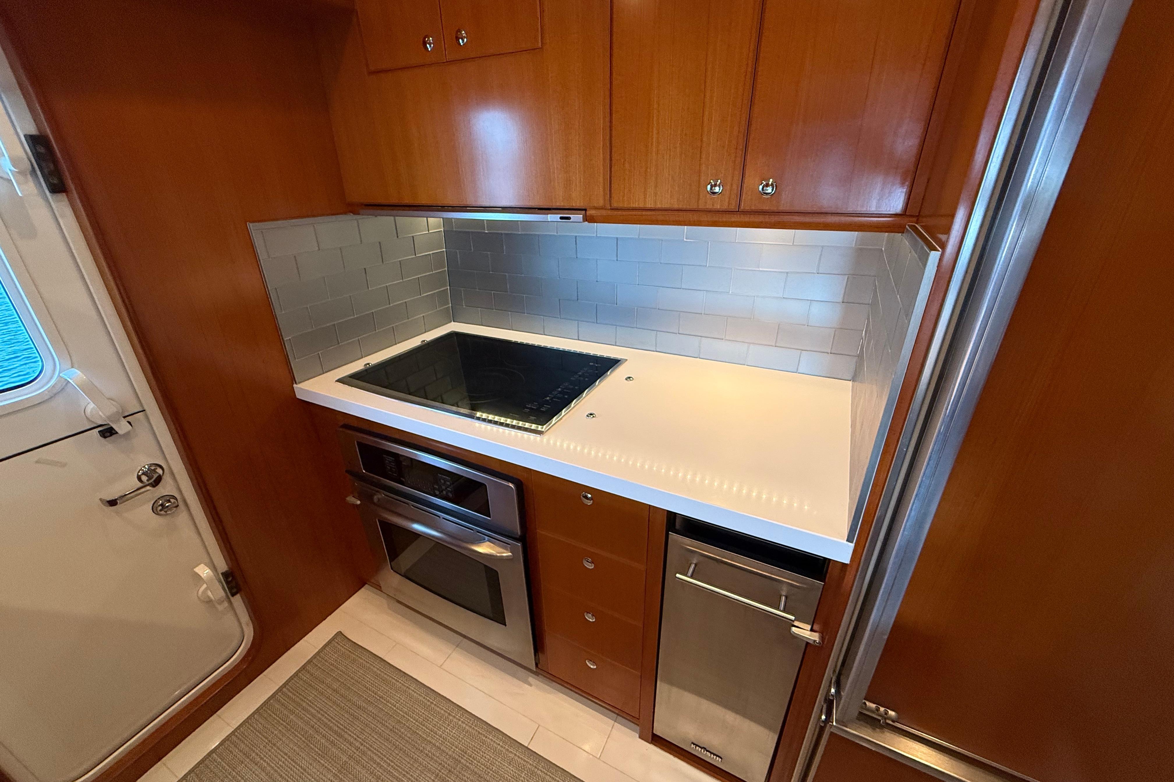 Compact kitchen in 2009 Nordhavn N64 yacht with modern appliances and wood cabinetry.