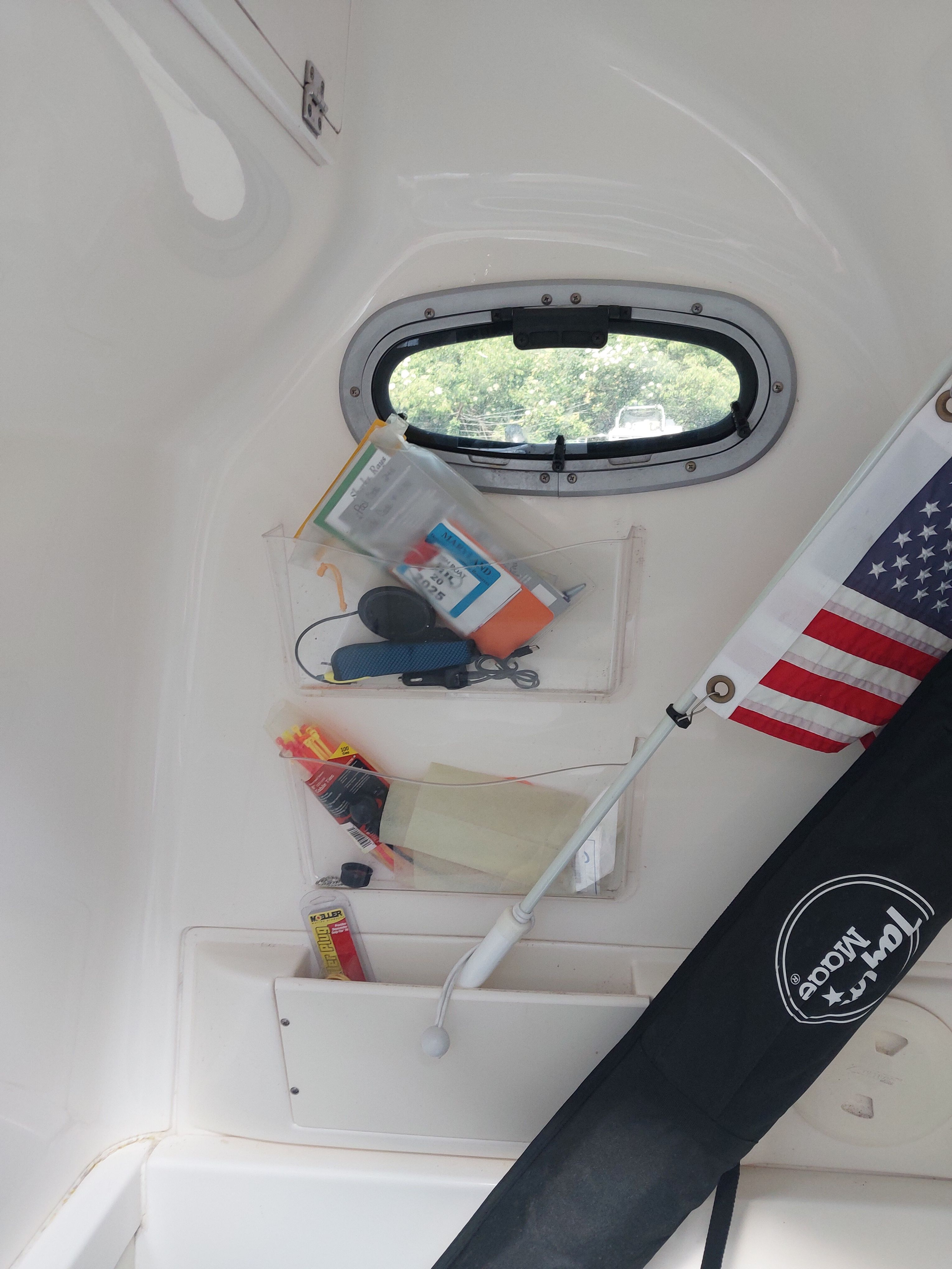 Interior of a boat with a window, a flag, and various items in pockets.