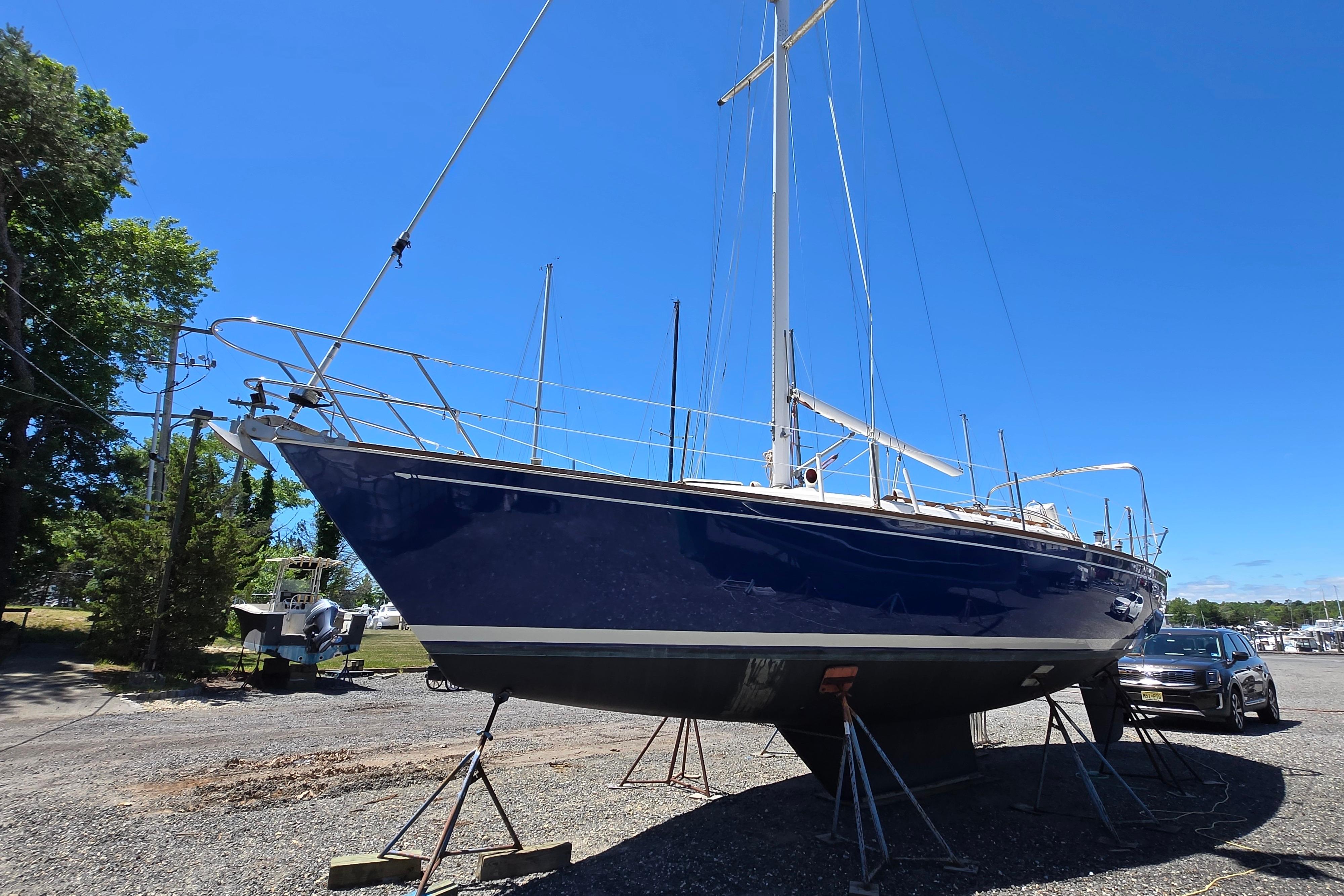 1988 Sabre 38 sailboat on stands, blue hull, clear sky background.