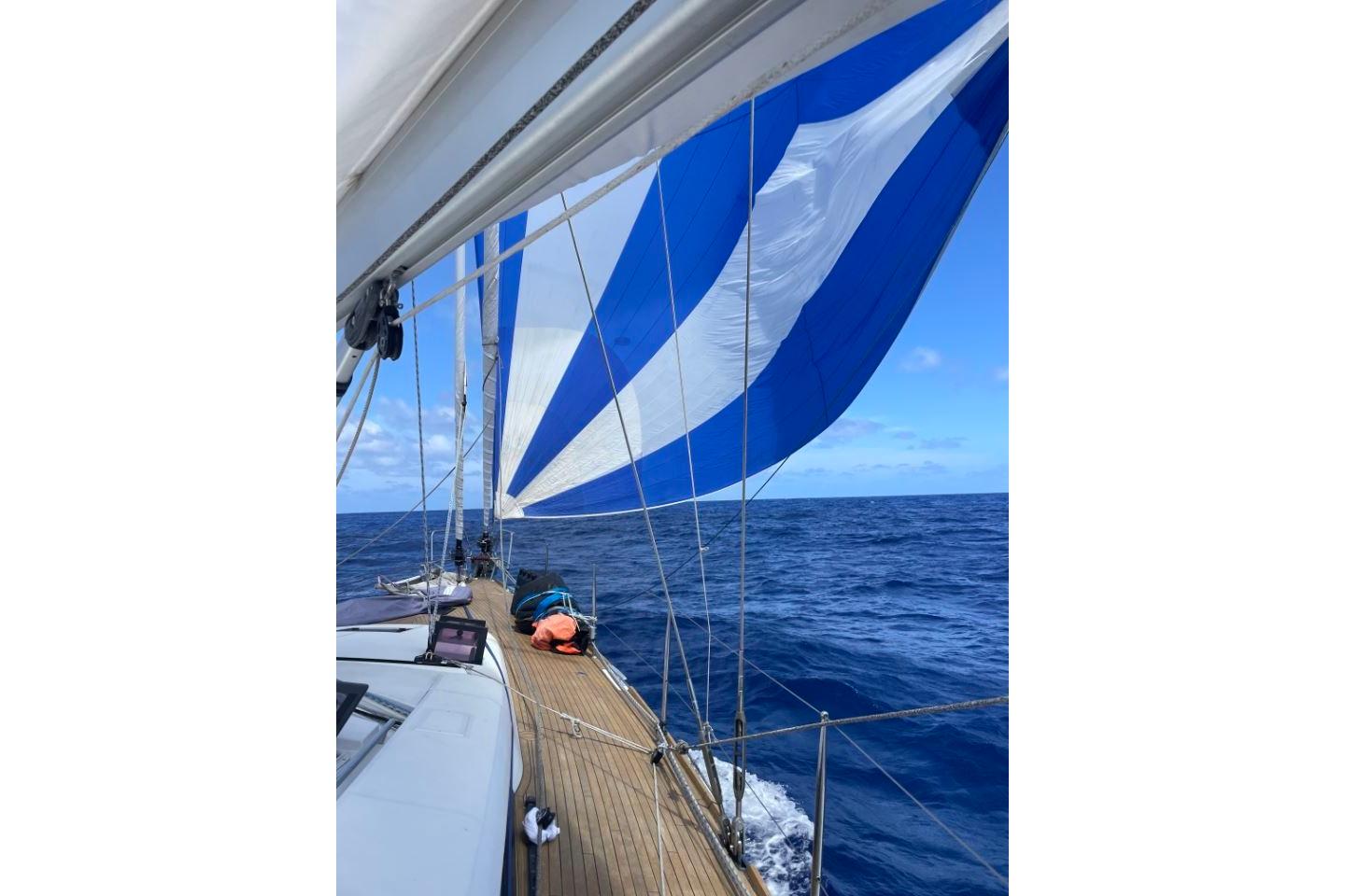 Sailing on a 2015 Beneteau Sense 55 with blue and white sails over open ocean.
