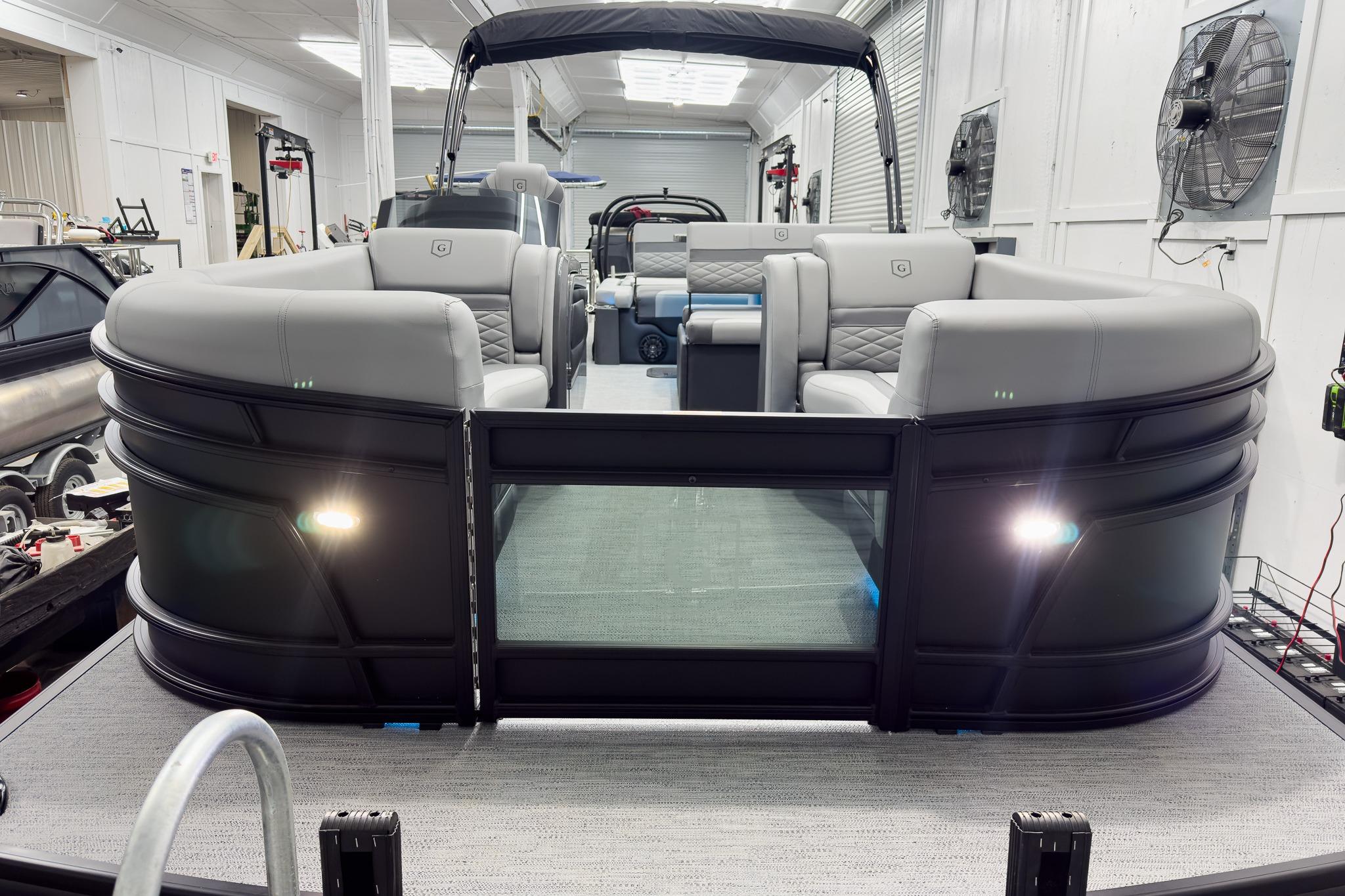 2026 Godfrey Monaco 25' Tritoon with luxurious seating in a showroom setting.
