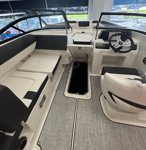 2024 Bayliner DX 2050 boat interior with seating, steering wheel, and storage compartment.