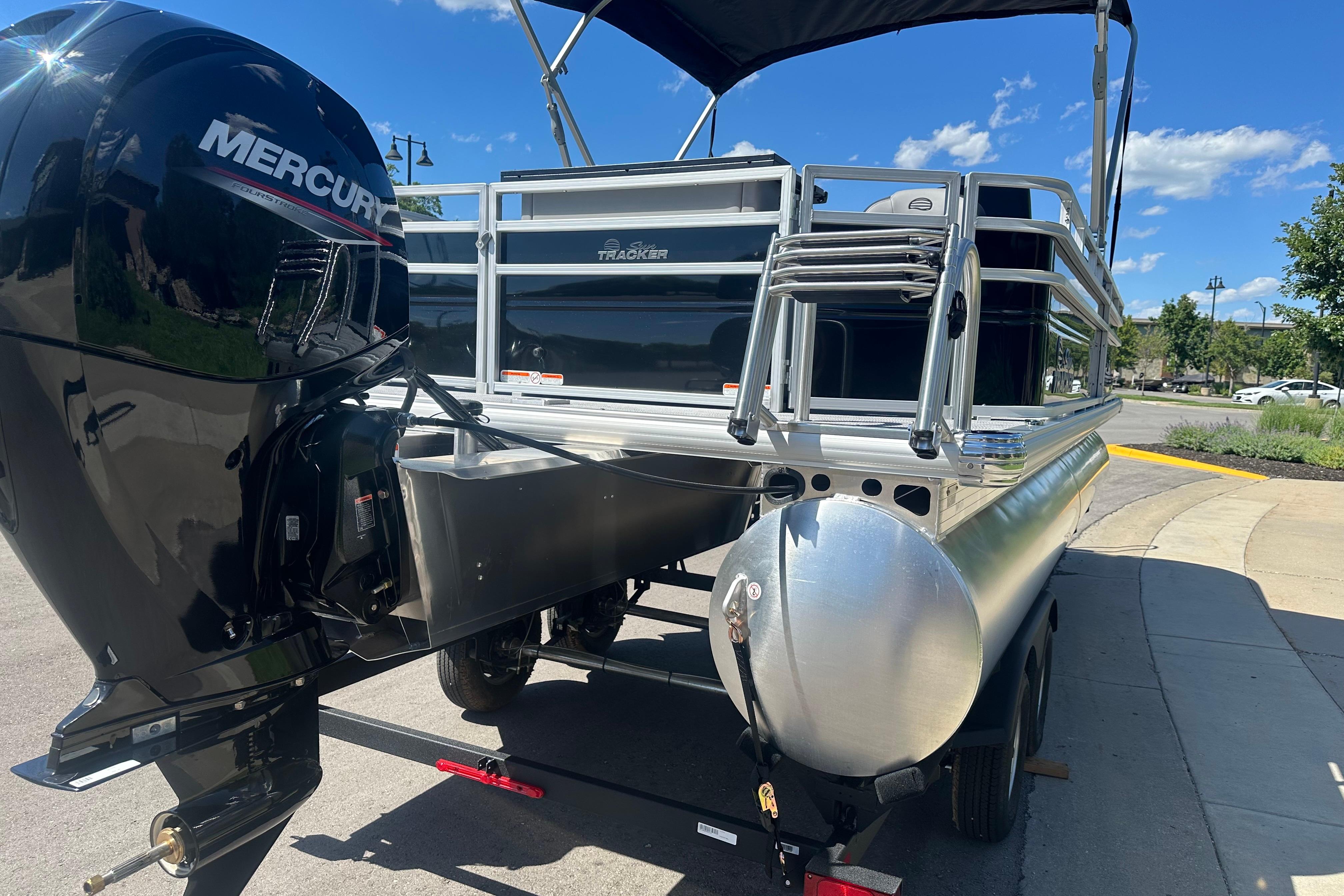 2026 Sun Tracker SportFish 22 DLX pontoon boat with Mercury engine, parked outdoors.