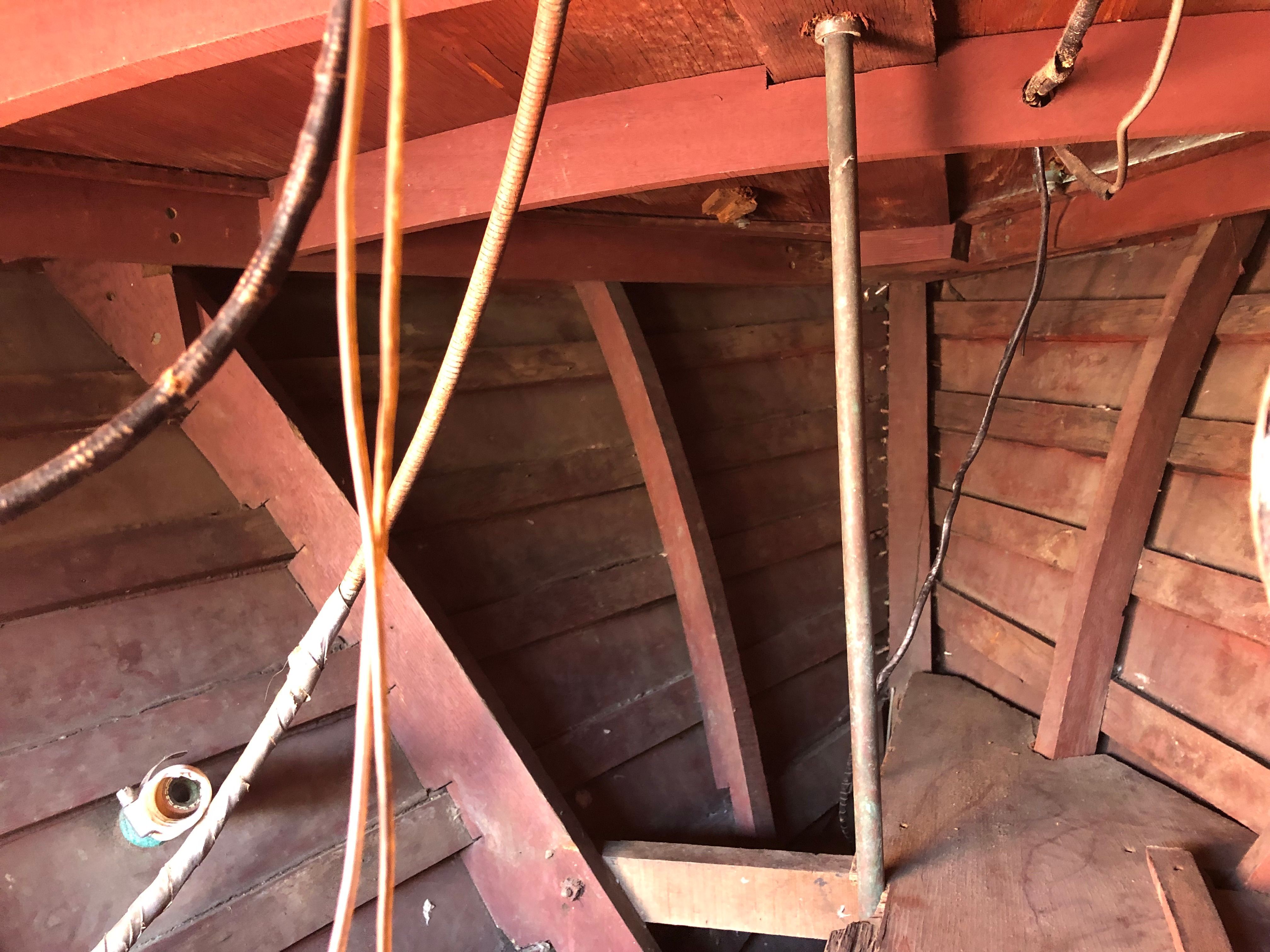 Interior view of a wooden boat hull with cables and metal rods.