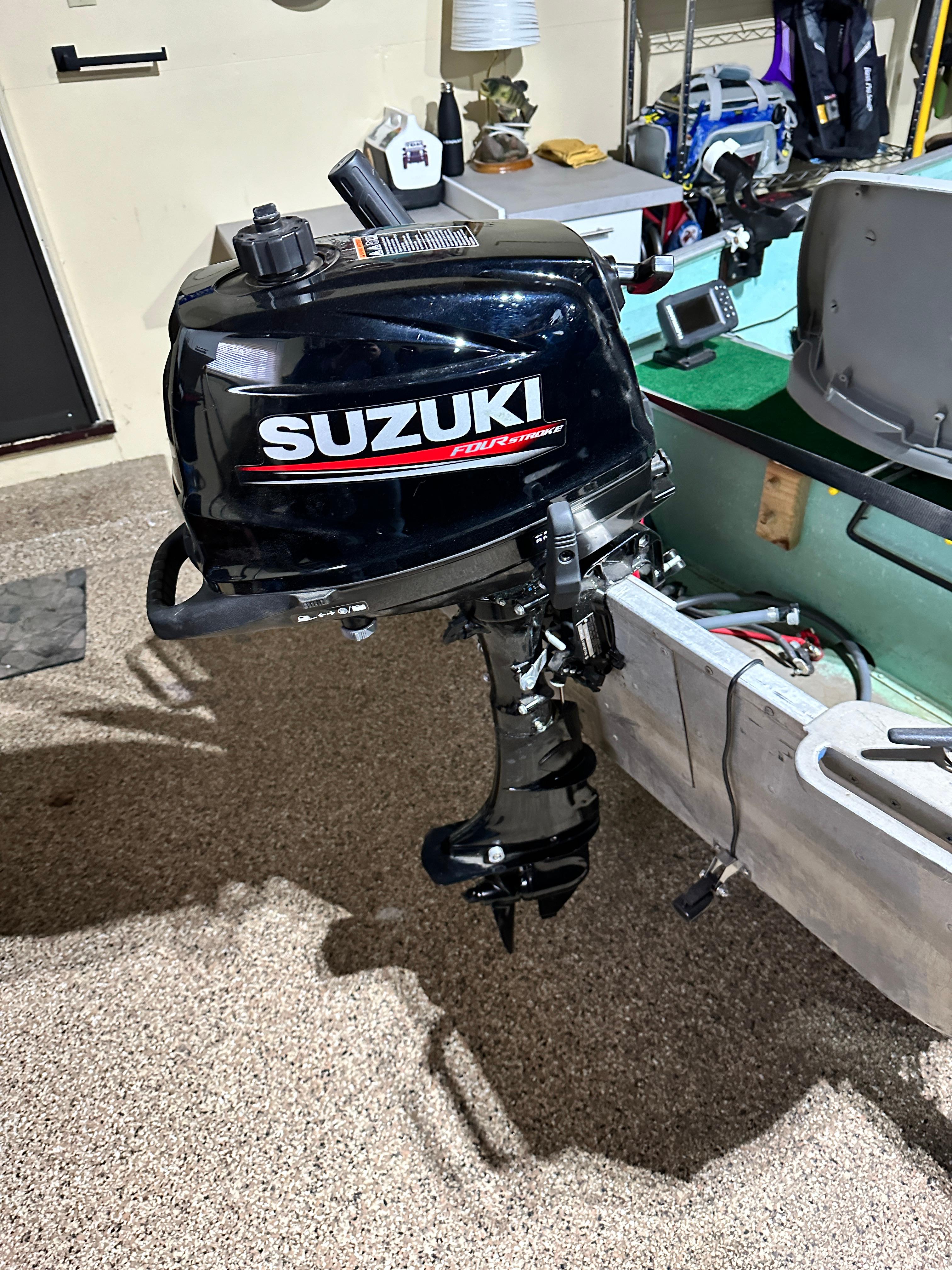 1960 Lund H boat with Suzuki outboard motor in a garage setting.