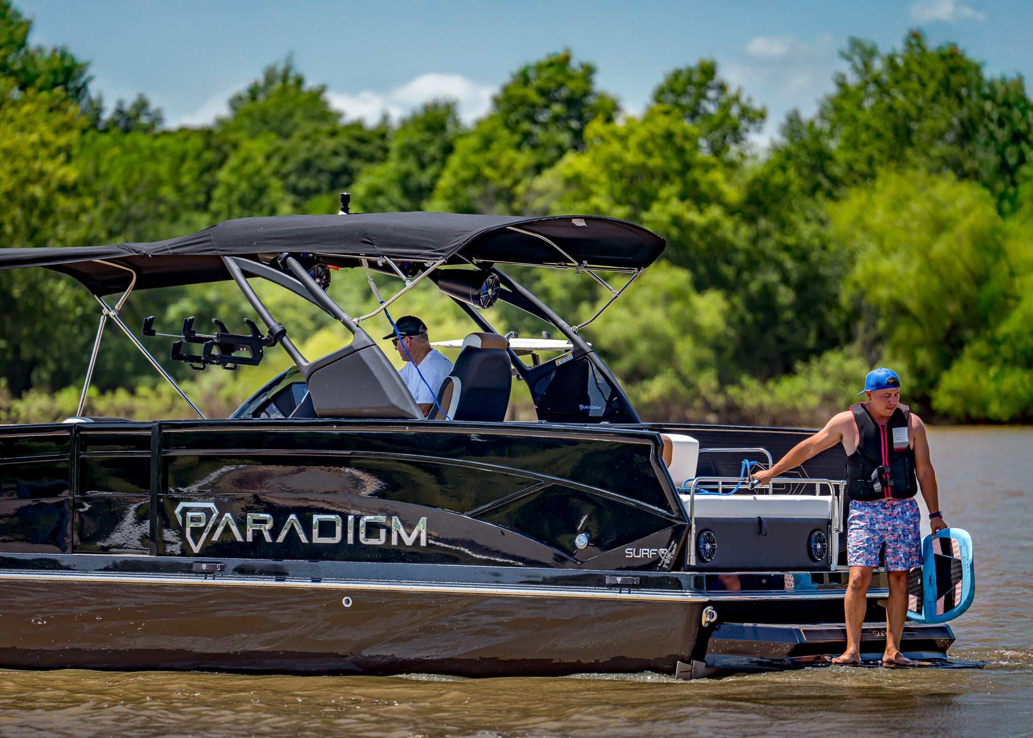 Pontoon boat Paradigm 236, 2025 model, cruising on a sunny lake with passengers.