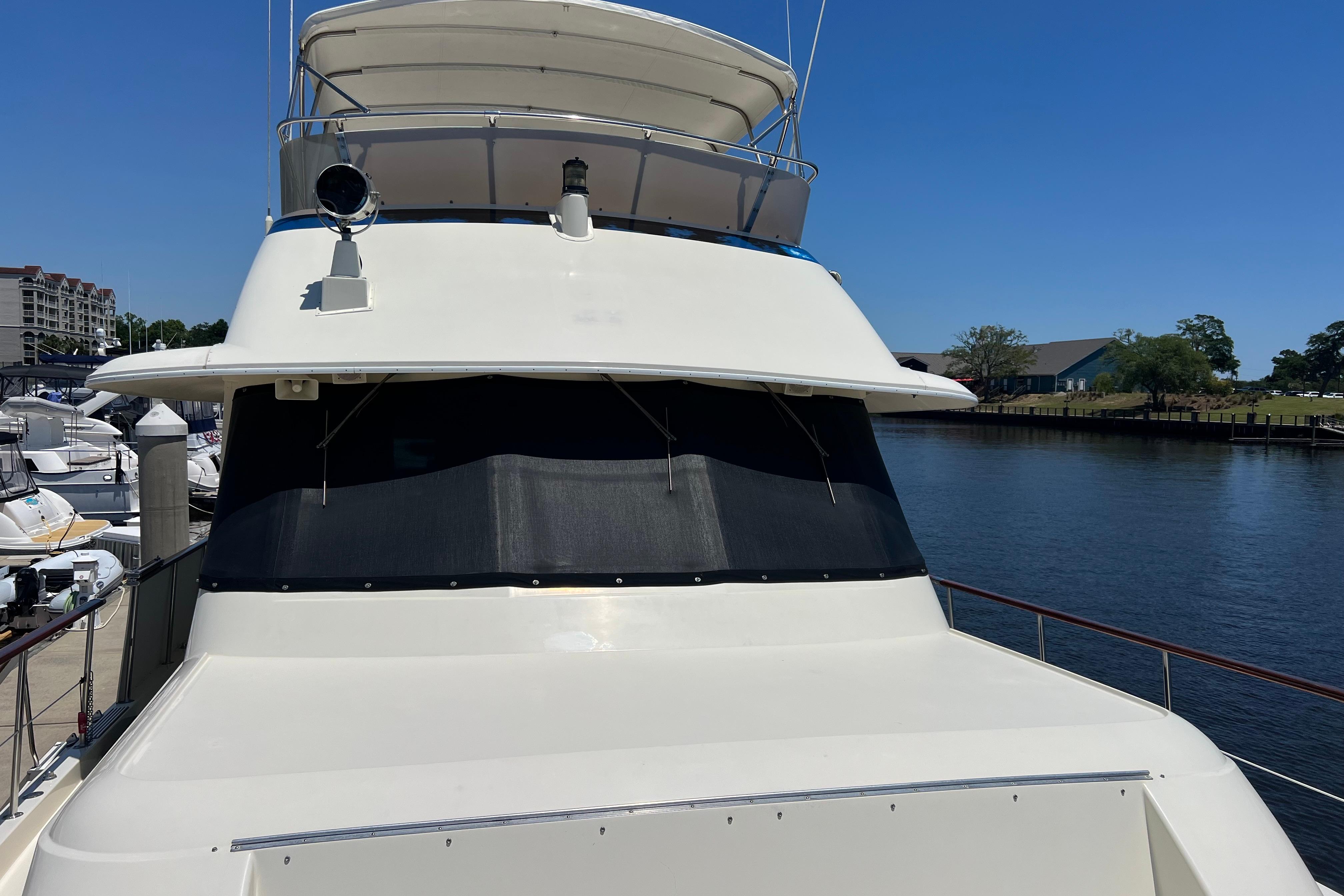 1987 Hatteras 70 Cockpit Motor Yacht docked at marina under clear blue sky.