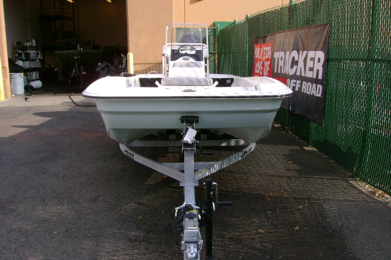2026 Mako Pro Skiff 17 CC boat on trailer, parked outdoors near a green fence.