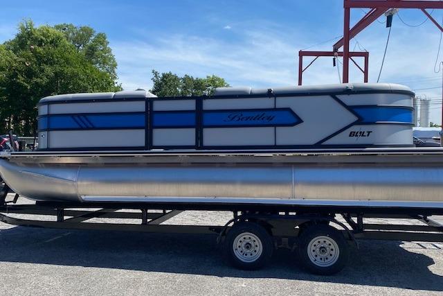 A 2026 Bentley Pontoons Bolt on a trailer, featuring a blue and gray design.