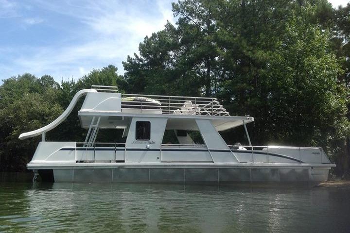 2008 Destination Yachts 45X14 houseboat with slide, docked near lush greenery.