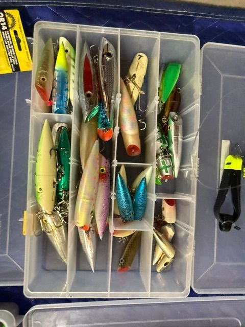 A tackle box with various colorful fishing lures and a tool.