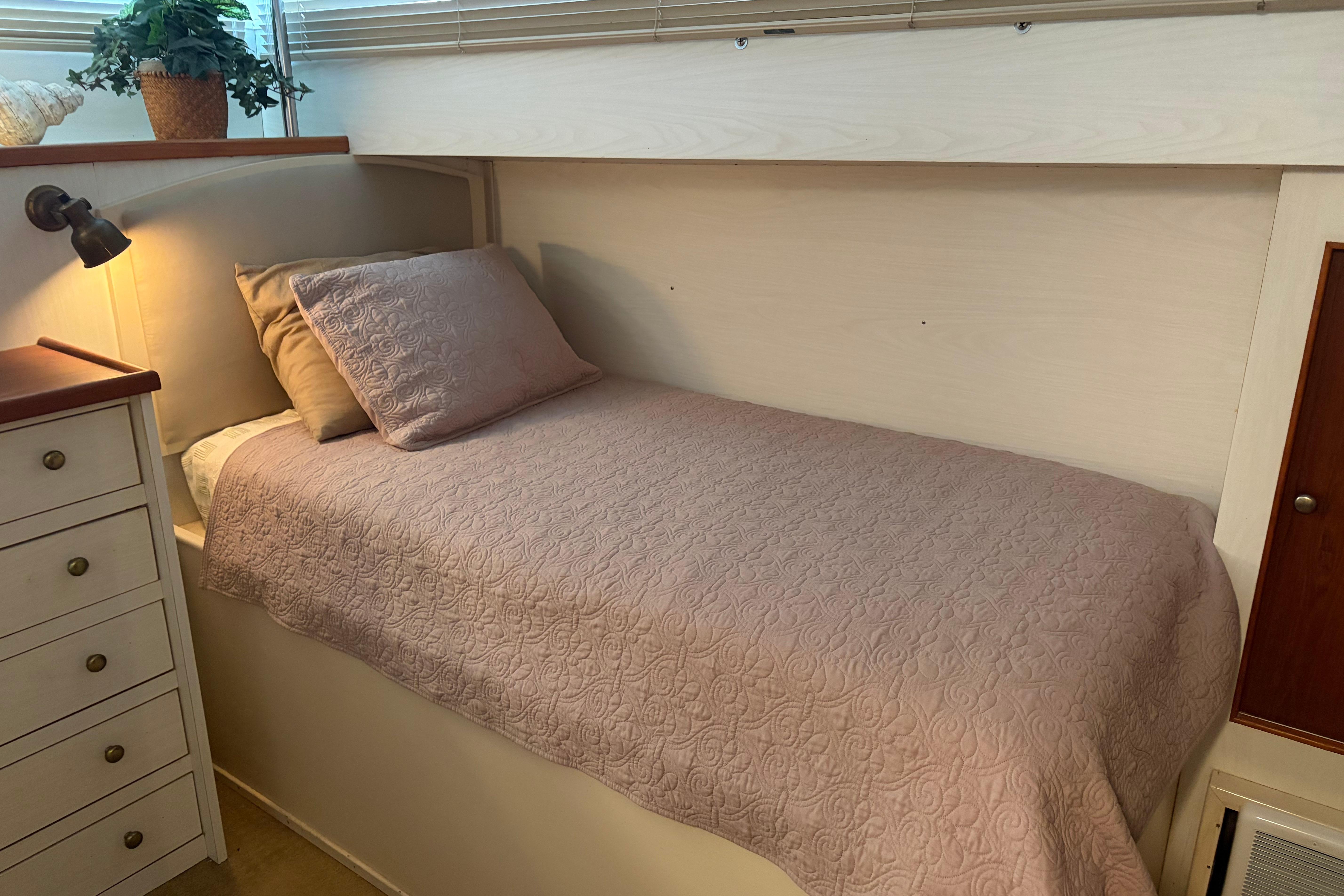 Cozy cabin bed in a 1971 Chris-Craft 42 Commander yacht, featuring elegant bedding and soft lighting.