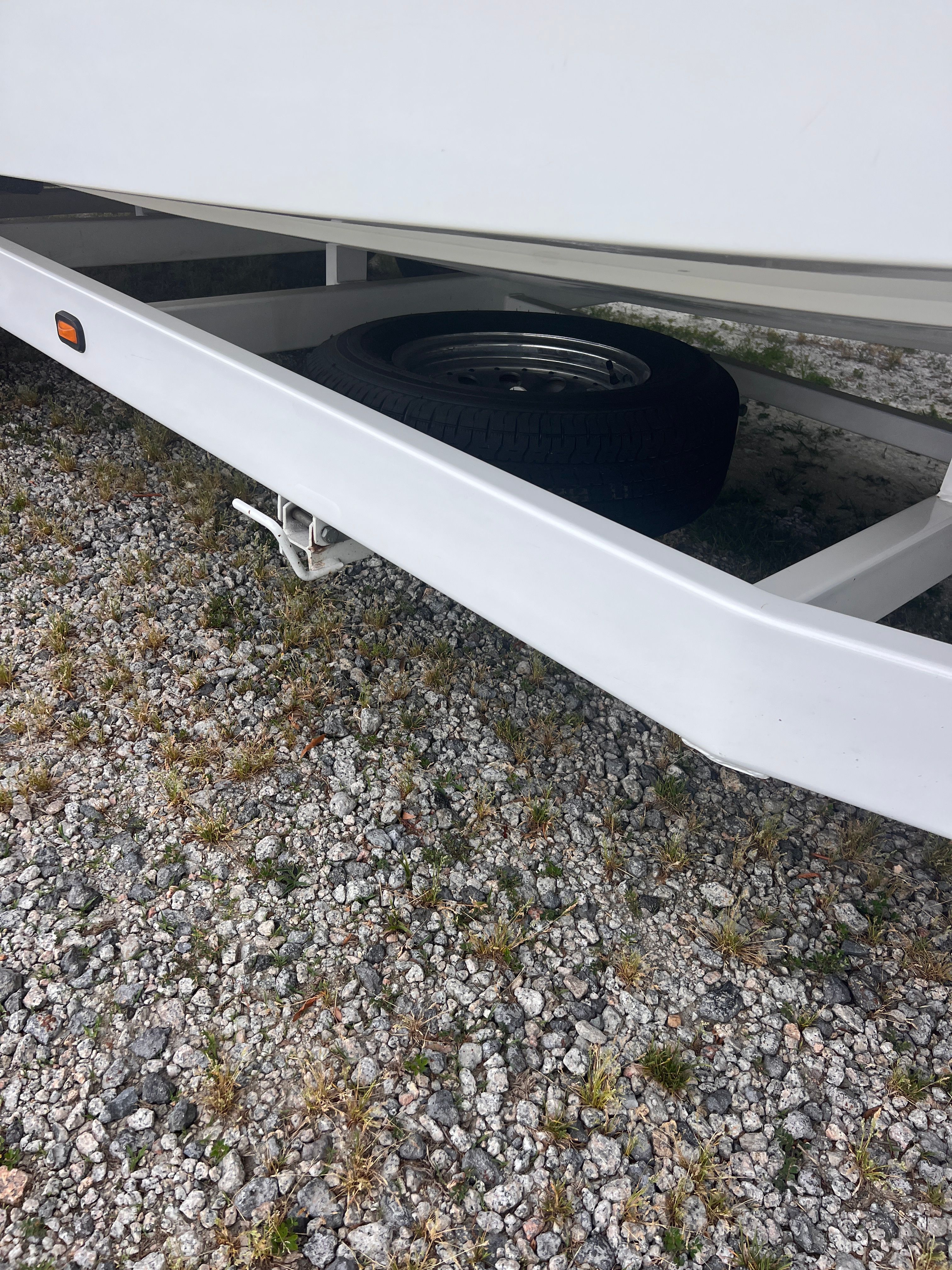 A boat trailer with a spare tire on a gravel surface.